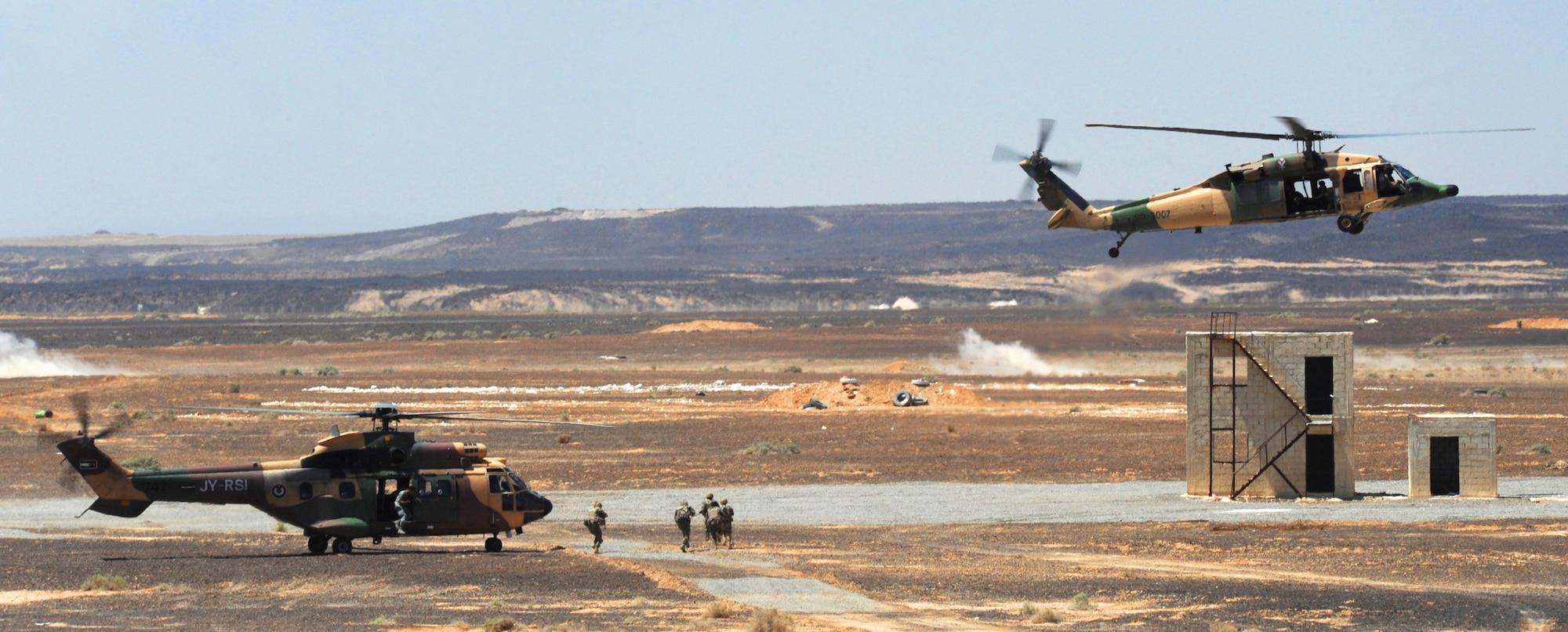 Special operations Service members from the Royal Jordanian Armed Forces unload from AS332 Super Puma and AH-1 Cobra helicopters during Exercise Eager Tiger May 14, 2014, at an air base in northern Jordan. The competition scored formations from the RJAF, U.S. Marine Corps and U.S. Air Force on their ability to accurately drop live munitions on target. (U.S. Air Force photo by Staff Sgt. Brigitte N. Brantley/Released)