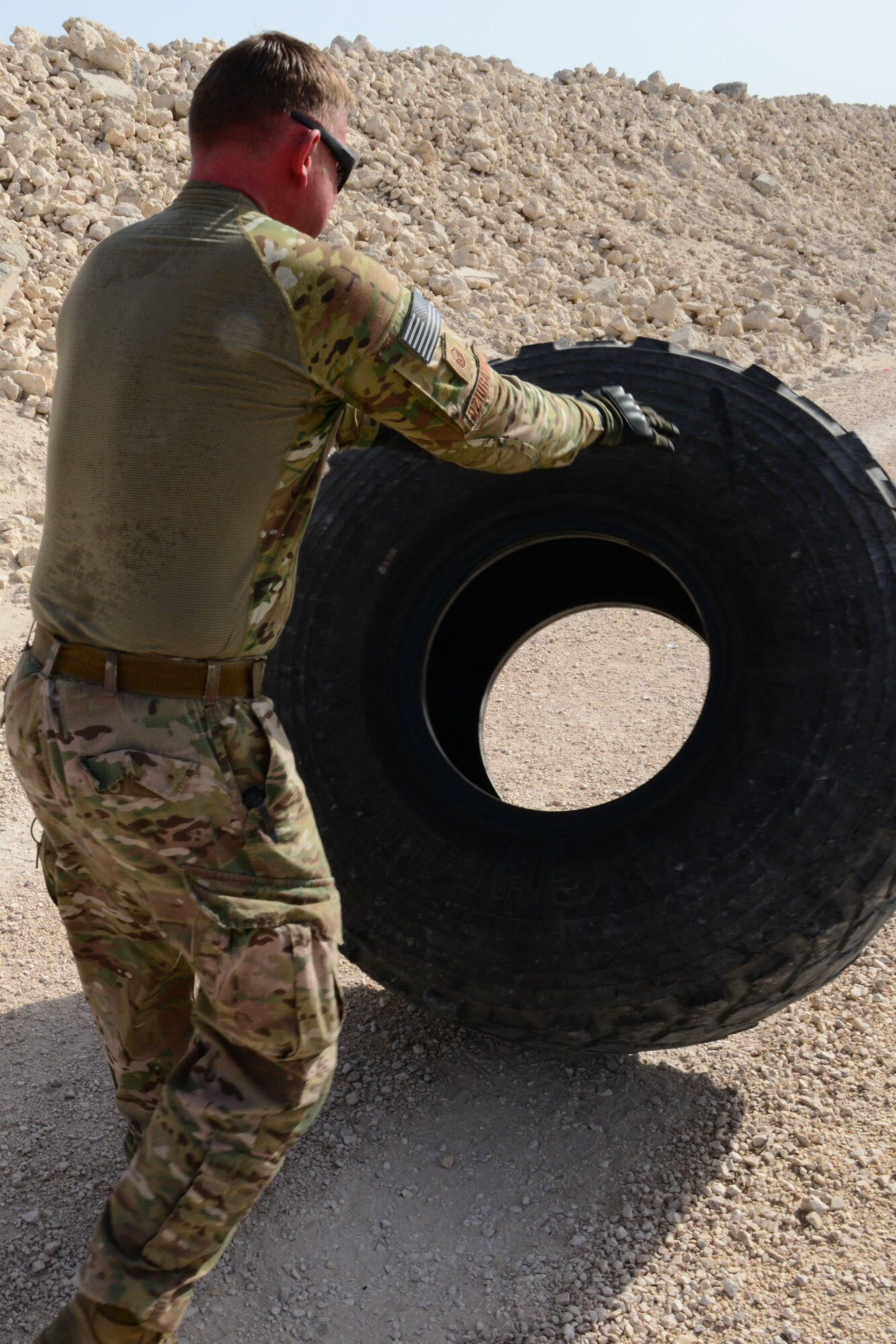U.S. Air Force Master Sgt. Marcin Dziurawiec, U.S. Central Command physical security noncommissioned officer, pushes a tire during a tire flip portion at an evasion challenge during National Police Week at Al Udeid Air Base, Qatar, May 15, 2014. National Police Week was first observed in 1962 when President John F. Kennedy signed its proclamation. Dziurawiec is deployed from Vandenberg Air Force Base, California and hails from Poland. (U.S. Air Force photo by Staff Sgt. Ciara Wymbs)