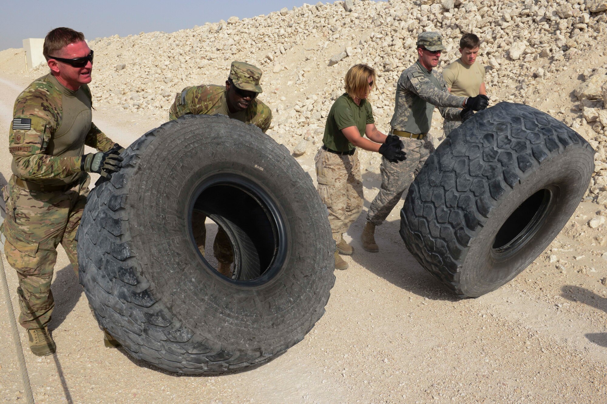 A joint military team completes the tire flip portion of an evasion challenge during National Police Week at Al Udeid Air Base, Qatar, May 15, 2014. The evasion challenge is one of several events in honor of National Police Week, which is to honor survivors and law enforcement members that have paid the ultimate sacrifice. (U.S. Air Force photo by Staff Sgt. Ciara Wymbs) 