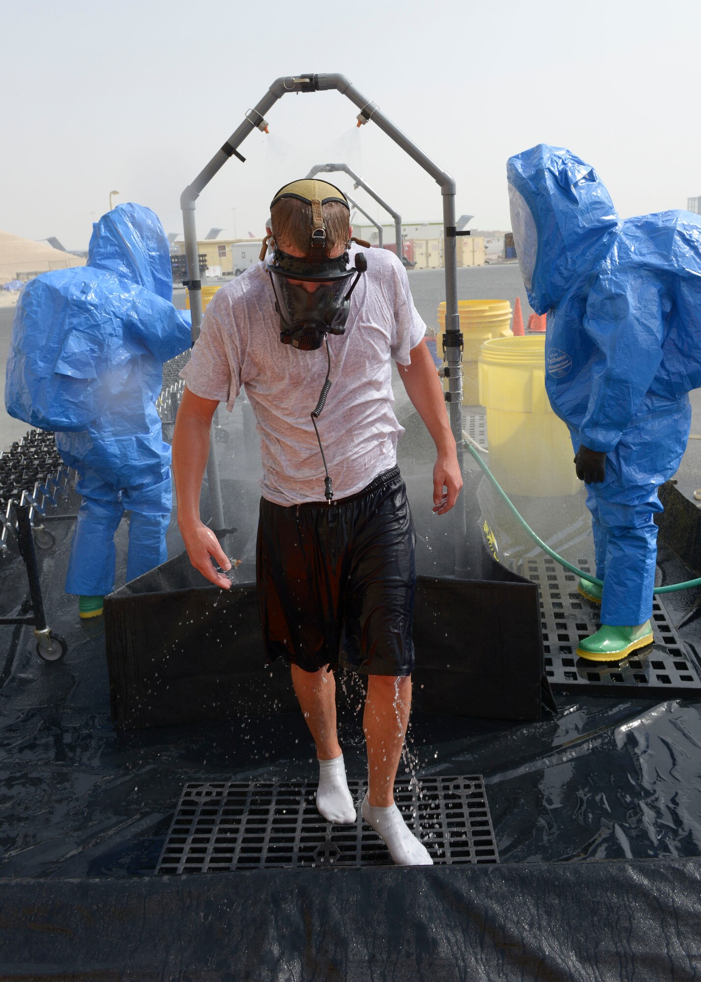 Airman First Class Kile Larsen, 379th Expeditionary Civil Engineer Squadron firefighter, is processed through the decontamination line during a hazardous materials qualification exercise May 10, at Al Udeid Air Base, Qatar. Decontamination reduces surface contamination by a continuous shower of water and removal of outer clothing. High-pressure, low-volume water flow is used to rinse off and dilute contaminants. Larsen’s home station is Joint Base Elmendorf-Richardson, Alaska, and his hometown is Emmett, Idaho (U.S. Air Force photo/Senior Airman Colin Cates