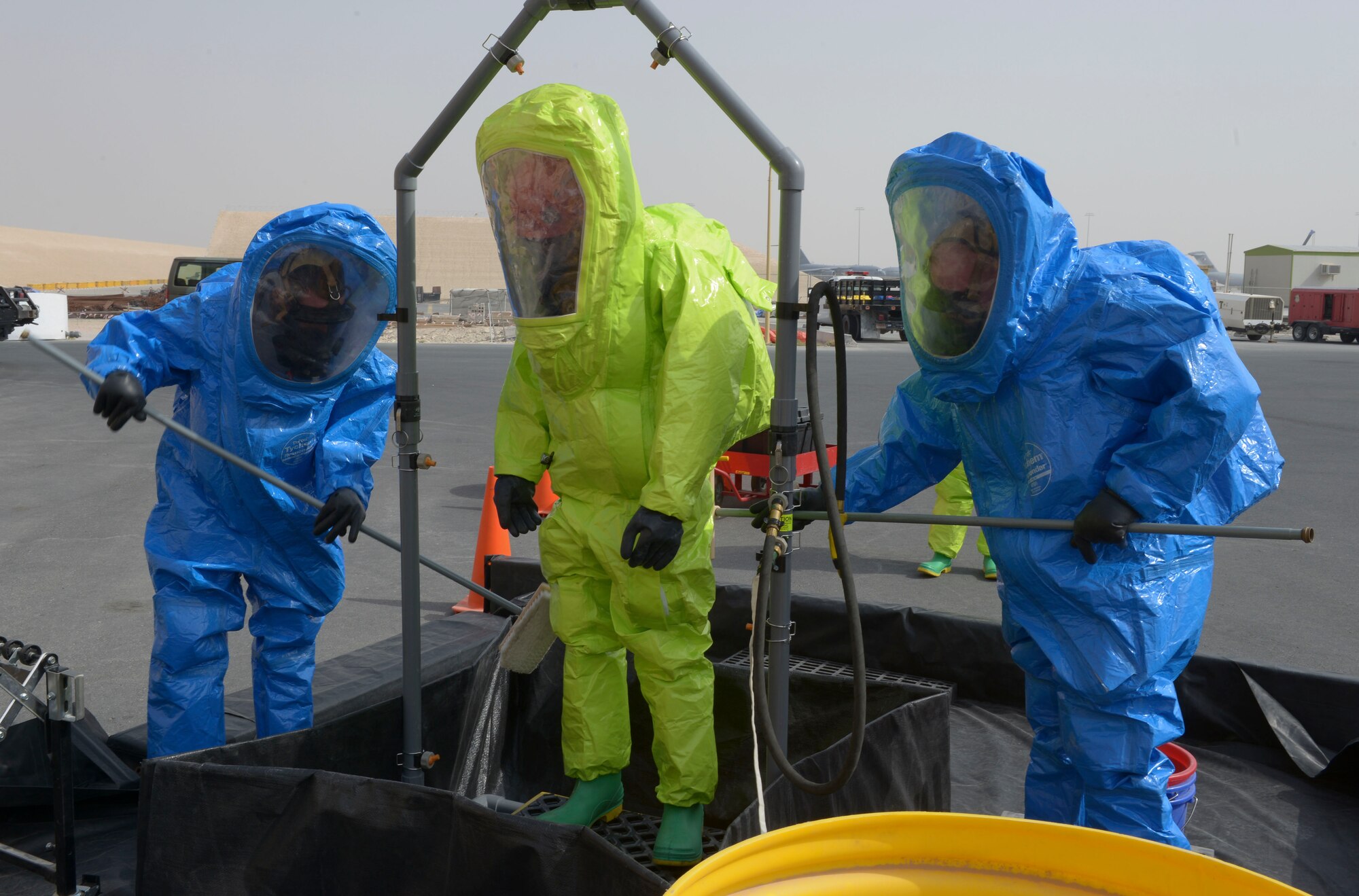 Airman First Class Kile Larsen, 379th Expeditionary Civil Engineer Squadron firefighter, is processed through the decontamination line during a hazardous materials qualification exercise May 10, at Al Udeid Air Base, Qatar. Decontamination reduces surface contamination by a continuous shower of water and removal of outer clothing. High-pressure, low-volume water flow is used to rinse off and dilute contaminants. Larsen’s home station is Joint Base Elmendorf-Richardson, Alaska, and his hometown is Emmett, Idaho (U.S. Air Force photo/Senior Airman Colin Cates