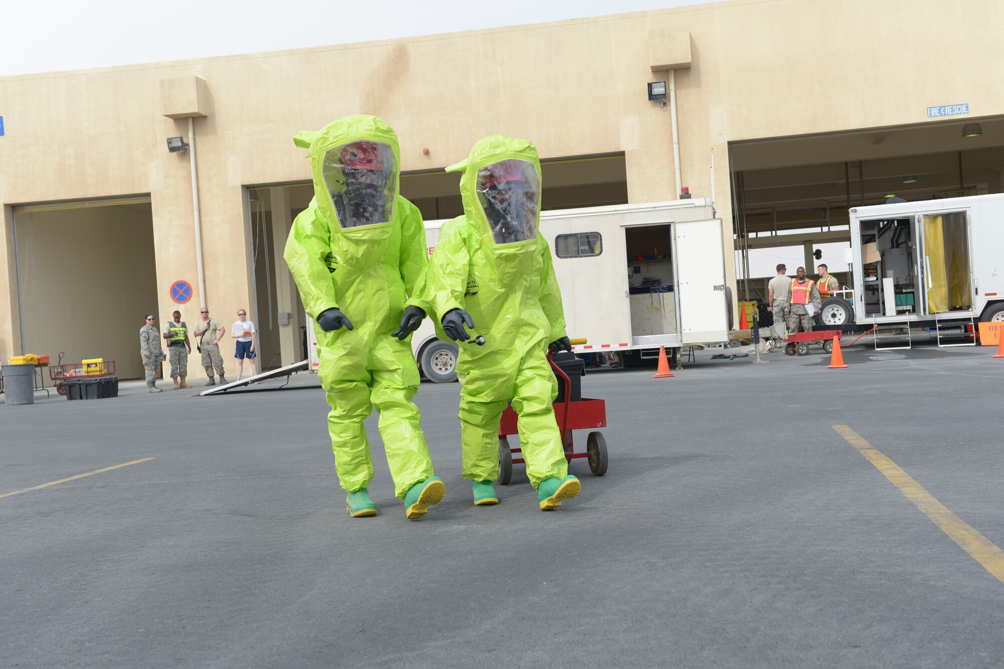 Senior Airman Chrisili Villasenor and Airman First Class Kile Larsen, 379th Expeditionary Civil Engineer Squadron firefighter, walk to the hazardous materials qualification site May 10, at Al Udeid Air Base, Qatar. The firefighters wore Level A Hazmat suits which provides the highest level of protection against vapors, gases, mists, and particles. Villasenor’s home station is Joint Base Langley-Eustis, Virginia, and his hometown is Siloam Springs, Arkansas. Larsen’s home station is Joint Base Elmendorf-Richardson, Alaska, and  his hometown is Emmett, Idaho. (U.S. Air Force photo/Senior Airman Colin Cates)