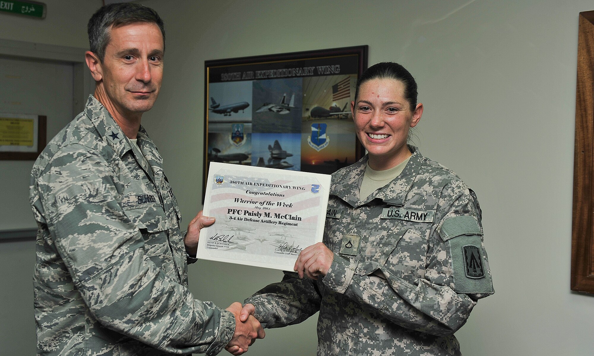 Air Force Brig. Gen. Kevin Schneider, 380th Air Expeditionary Wing commander, presented Army Pfc. Paisly McClain, petroleum heavy equipment vehicle operator, with the warrior of the week certificate at an undisclosed area in Southwest Asia, May 7, 2014. McClain is a native of Austin, Texas, and is deployed from Fort Bragg, N.C.