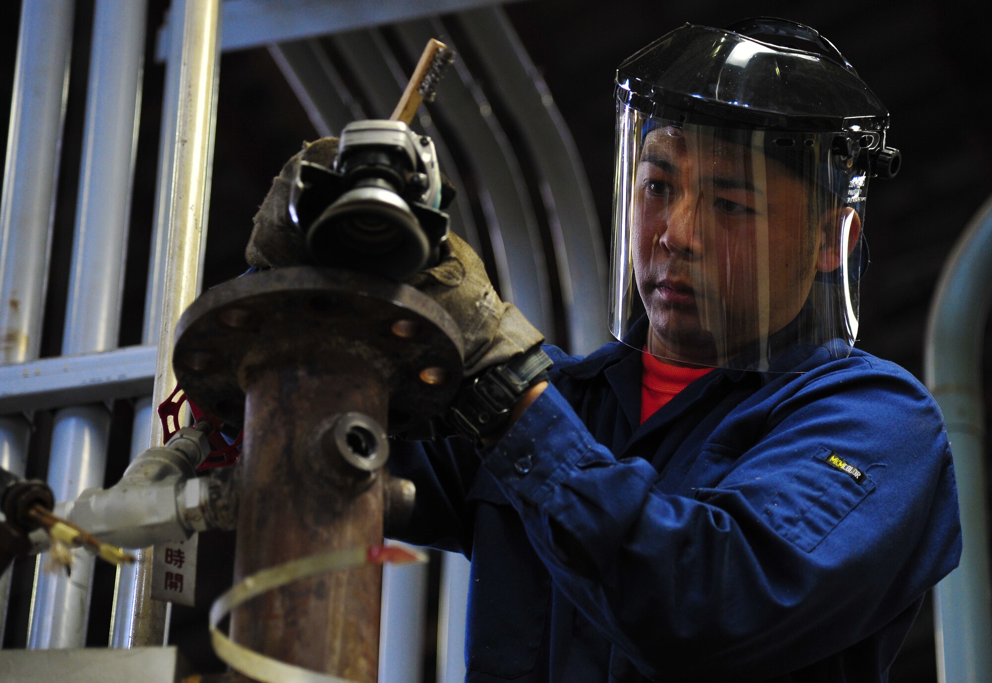 Ohsaka Takashi, 35th Civil Engineer Squadron boiler operator, cleans an outer compartment at Misawa Air Base, Japan, May 16, 2014.. The base is currently in the process of turning off the heating systems on base to conserve energy and in turn save dollars. Personnel from the 35th Civil Engineer Squadron are able to begin maintenance on valves turned off. (U.S. Air Force photo/Senior Airman Jose Hernandez-Domitilo)