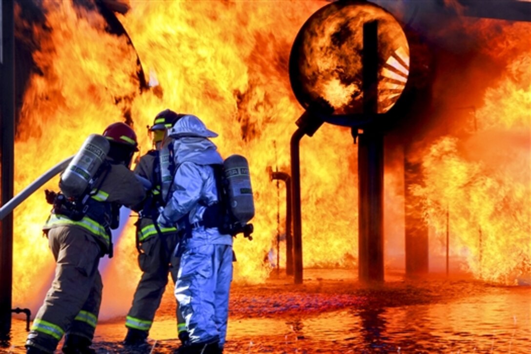 Air Force firefighters extinguish a training aircraft fire at the burn pit on Altus Air Force Base, Okla., May 2, 2014. The airmen, assigned to the 97th Civil Engineer Squadron, train monthly to maintain skill efficiency for emergencies. The squadron's firefighters allowed commanders to put out an aircraft fire to have a better understanding of the procedures to successfully extinguish a fire.
