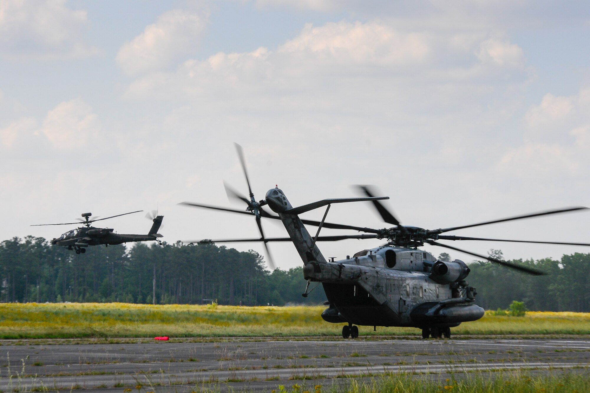 A U.S. Army AH-64 Apache lifts off from the left as a U.S. Marine CH-53 Sea Stallion taxis on the right during forward air refueling point operations at McEntire Joint National Guard Base, S.C. on May 14, 2014.  Elements of the South Carolina Air and Army National Guard and the U.S. Marines conduct joint operations which are crucial to the ongoing success of operational readiness and deployments around the world.  (U.S. Air National Guard photo by Tech Sgt. Jorge Intriago/Released)