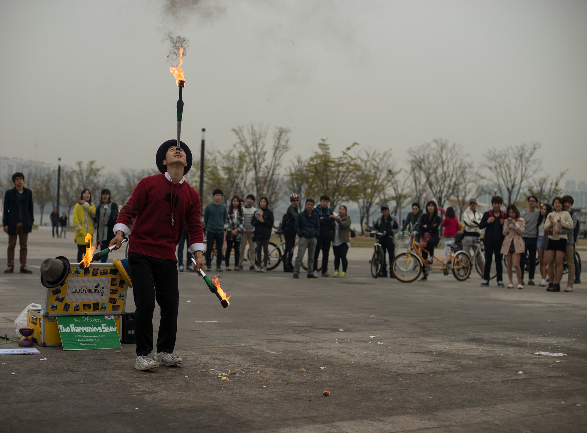 A street entertainer balances a flaming torch on his nose in Yeouido Park April 12, 2014, in Seoul, Republic of Korea. The performer, who wore a sweater with Charlie Chaplain on it, performed several juggling tricks with fire and knives for the crowd. (U.S. Air Force photo by Staff Sgt. Jake Barreiro)