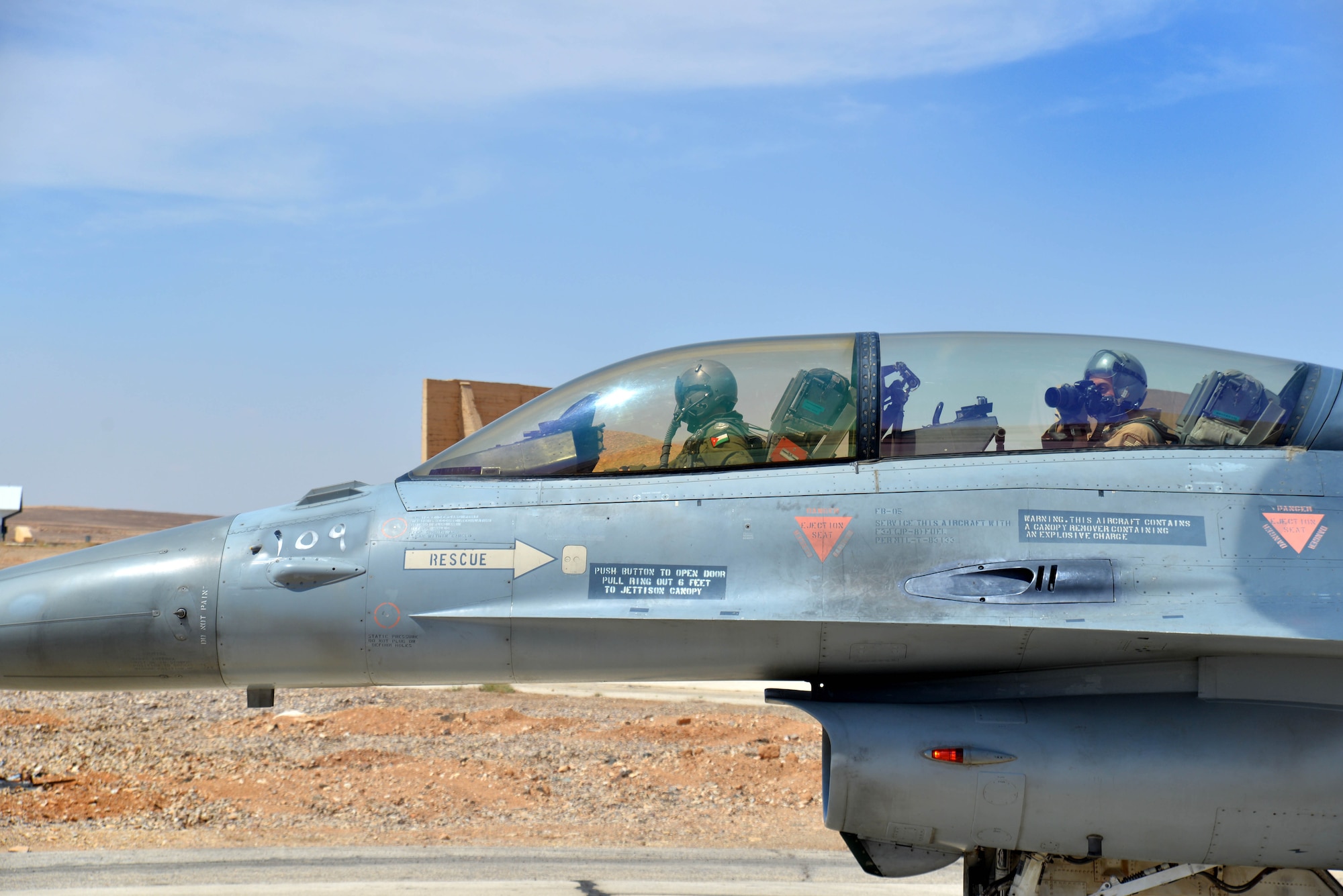 Staff Sgt. Roidan Carlson, 2d Combat Camera Squadron aerial combat broadcaster, and Royal Jordanian Air Force Lt. Col. Firas Masadeh, a flying wing commander, taxi in an RJAF F-16 Fighting Falcon before an aerial photography mission May 13, 2014, at an air base in northern Jordan. This flight took place during Exercise Eager Tiger to capture the partnership between U.S. and Jordan. (U.S. Air Force photo by Capt. Sara Greco/Released)