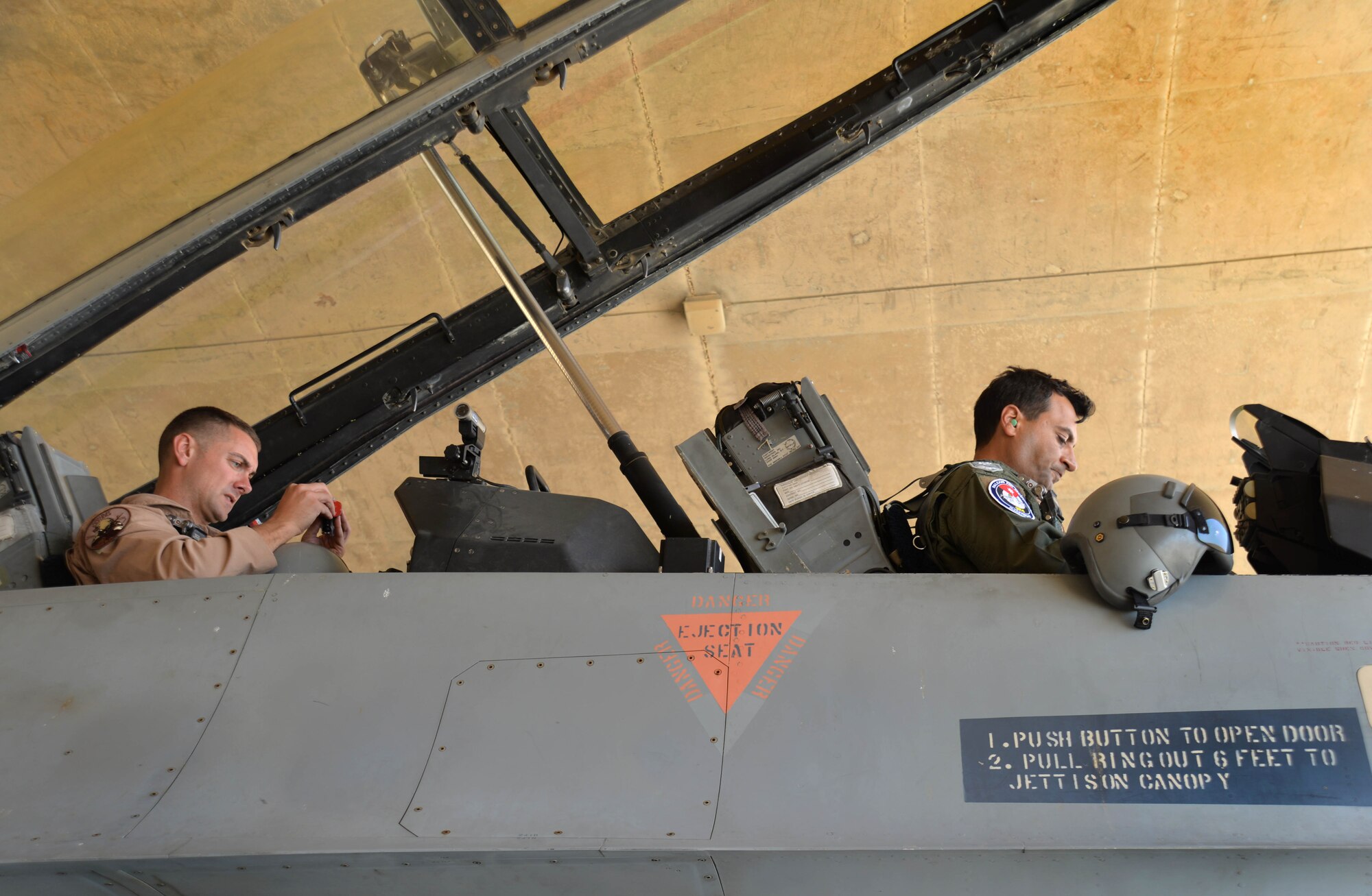 Staff Sgt. Roidan Carlson, 2d Combat Camera Squadron aerial combat broadcaster, and Royal Jordanian Air Force Lt. Col. Firas Masadeh, a flying wing commander, each prepare their equipment before an aerial photography mission May 13, 2014, at an air base in northern Jordan. Carlson was assigned to capture pictures of  fighter aircraft from the Royal Jordanian Air Force, U.S. Air Force and U.S. Marine Corps in formation over iconic areas of Jordan during Exercise Eager Tiger. (U.S. Air Force photo by Capt. Sara Greco/Released)