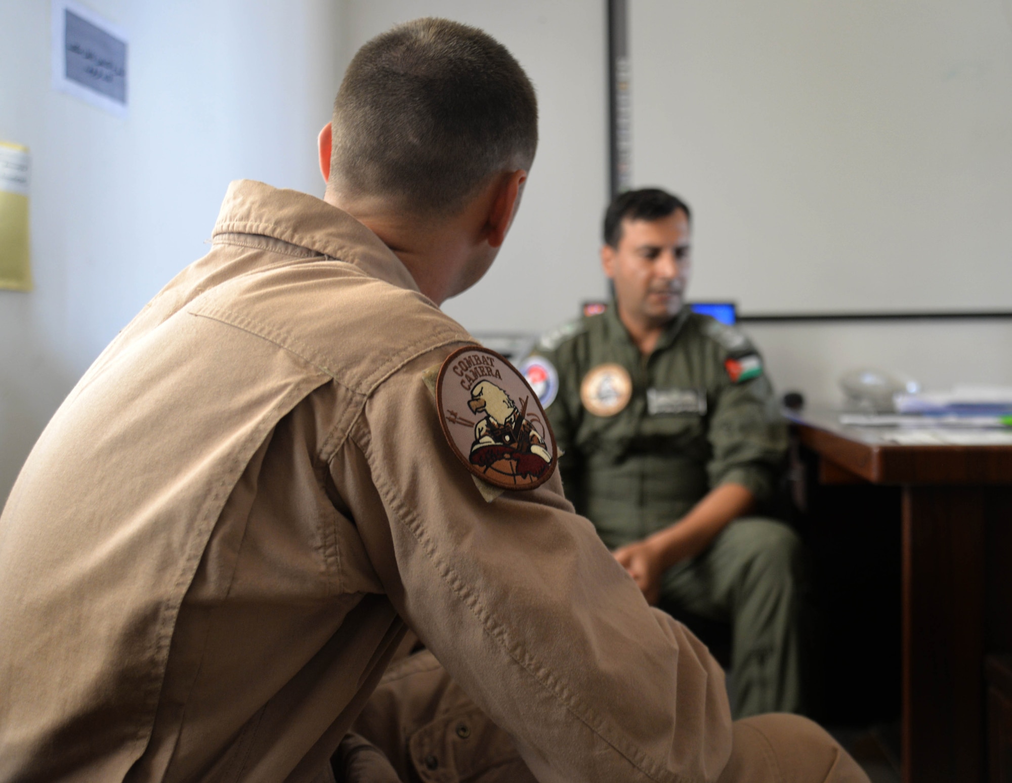 Staff Sgt. Roidan Carlson, 2d Combat Camera Squadron aerial combat broadcaster, receives a pre-flight briefing from Royal Jordanian Air Force Lt. Col. Firas Masadeh, a flying wing commander, May 13, 2014, at an air base in northern Jordan. They flew in formation with two Royal Jordanian Air Force F-16 Fighting Falcons, a U.S. F-16, and a U.S. F-18 Hornet over iconic areas of Jordan during Exercise Eager Tiger to commemorate the partnership between U.S and Jordan. (U.S. Air Force photo by Capt. Sara Greco/Released)