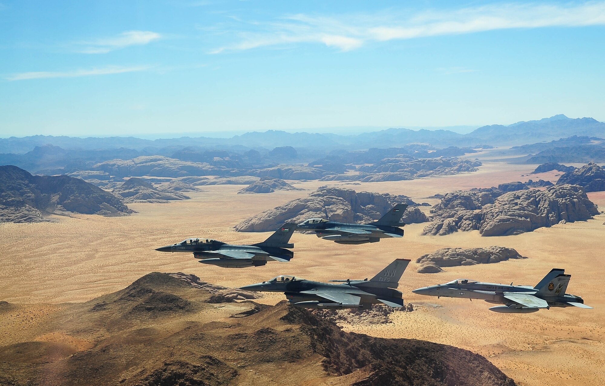 F-16 Fighting Falcons from the U.S. and Royal Jordanian air forces, as well as an F-18 Hornet from the U.S. Marine Corps, fly over the Wadi Rum desert, Jordan May 13, 2014, during Exercise Eager Tiger. Hosted annually in Jordan, the exercise allows fighter pilots and maintainers from around the world to exchange knowledge while increasing interoperability and showing their dedication to regional stability. (U.S. Air Force photo by Staff Sgt. Roidan Carlson/Released)