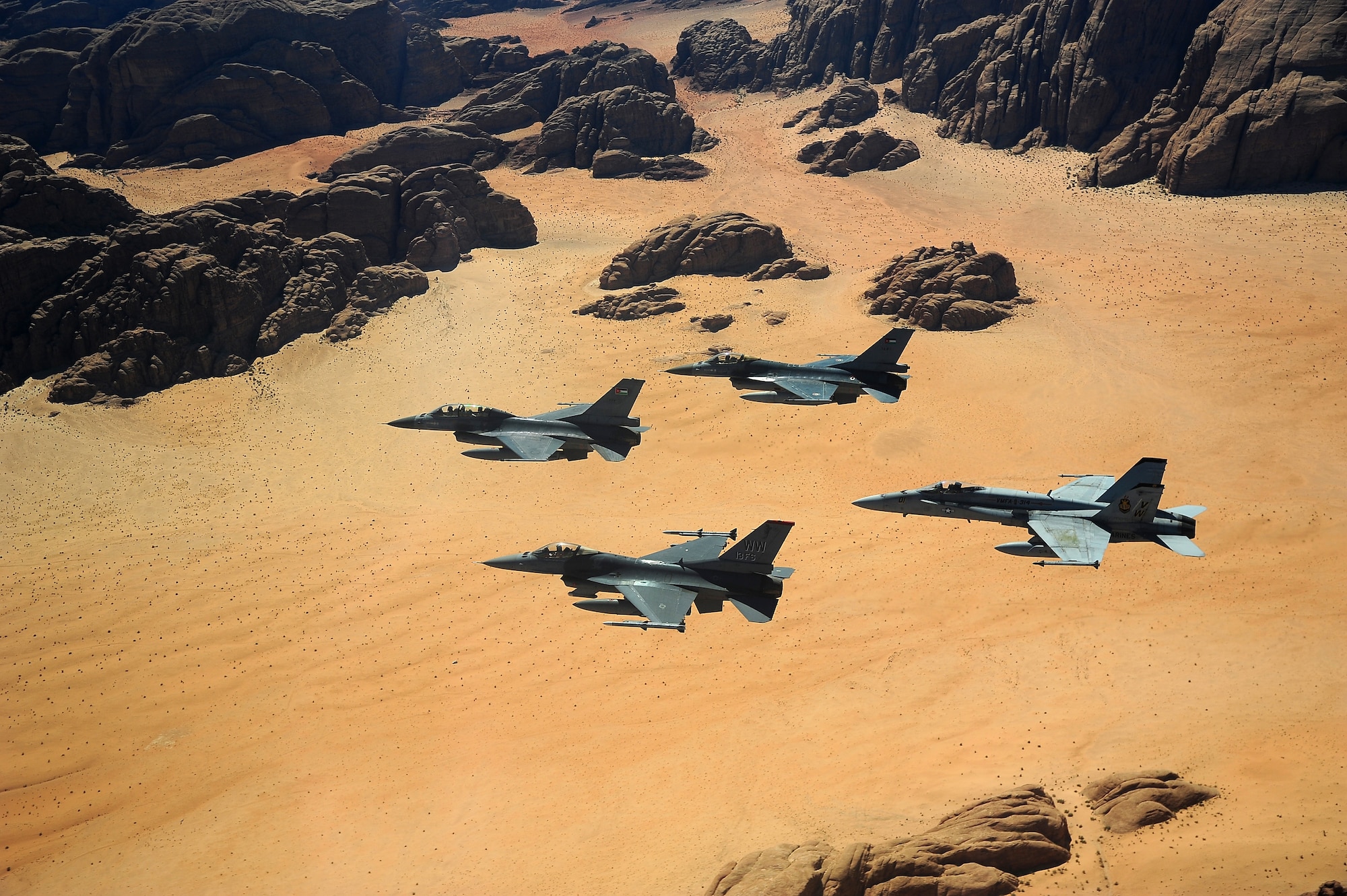 F-16 Fighting Falcons from the U.S. and Royal Jordanian air forces, as well as an F-18 Hornet from the U.S. Marine Corps, fly over the Wadi Rum desert, Jordan May 13, 2014, during Exercise Eager Tiger. Hosted annually in Jordan, the exercise allows fighter pilots and maintainers from around the world to exchange knowledge while increasing interoperability and showing their dedication to regional stability. (U.S. Air Force photo by Staff Sgt. Roidan Carlson/Released)