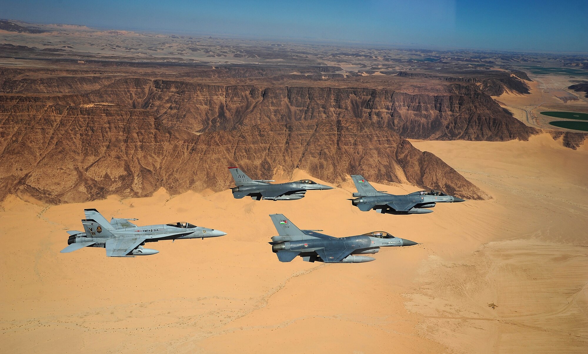 F-16 Fighting Falcons from the U.S. and Royal Jordanian air forces, as well as an F-18 Hornet from the U.S. Marine Corps, fly over the Wadi Rum desert, Jordan May 13, 2014, during Exercise Eager Tiger. Hosted annually in Jordan, the exercise allows fighter pilots and maintainers from around the world to exchange knowledge while increasing interoperability and showing their dedication to regional stability. (U.S. Air Force photo by Staff Sgt. Roidan Carlson/Released)