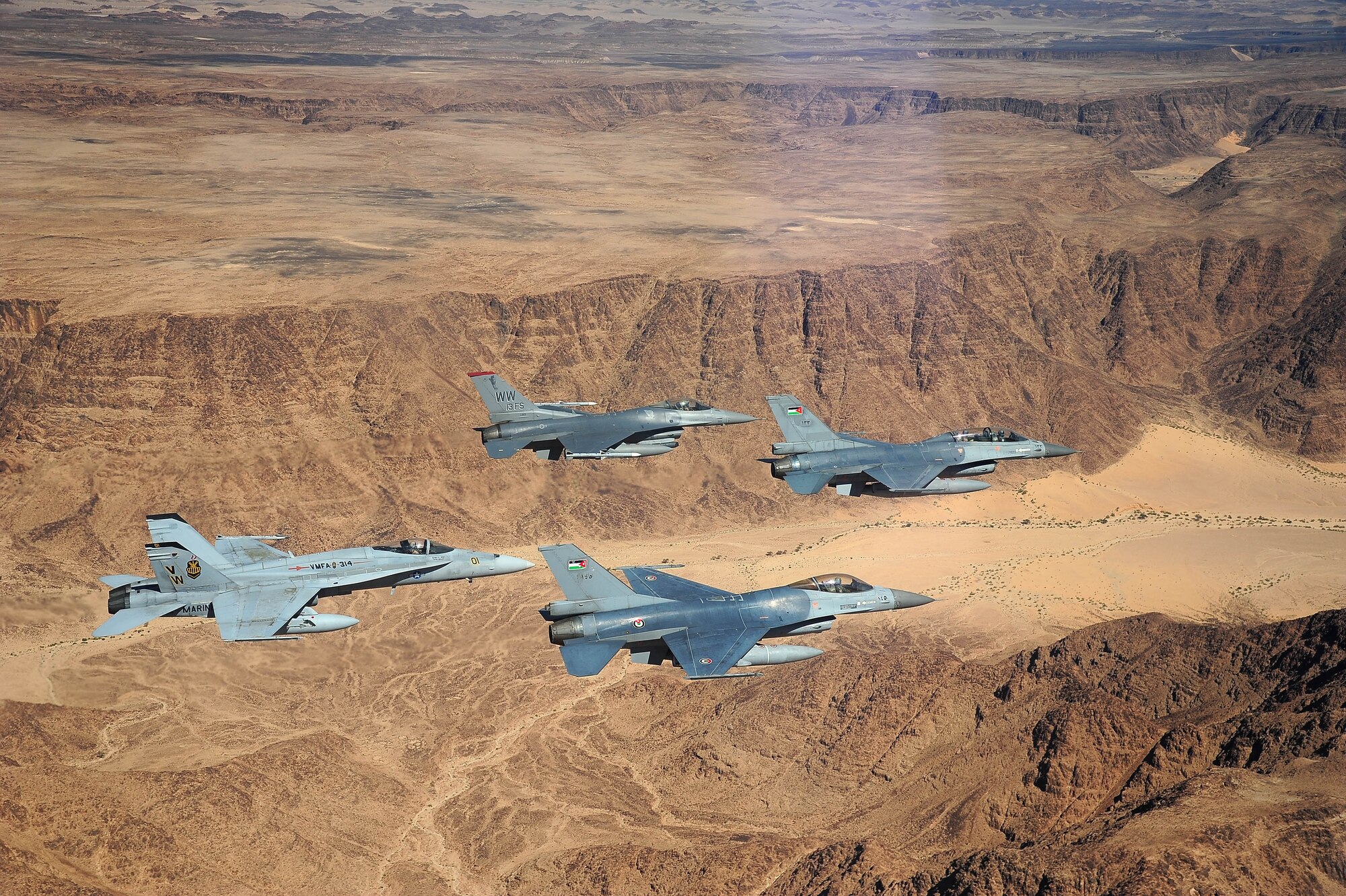 F-16 Fighting Falcons from the U.S. and Royal Jordanian air forces, as well as an F-18 Hornet from the U.S. Marine Corps, fly over the Wadi Rum desert, Jordan May 13, 2014, during Exercise Eager Tiger. Hosted annually in Jordan, the exercise allows fighter pilots and maintainers from around the world to exchange knowledge while increasing interoperability and showing their dedication to regional stability. (U.S. Air Force photo by Staff Sgt. Roidan Carlson/Released)