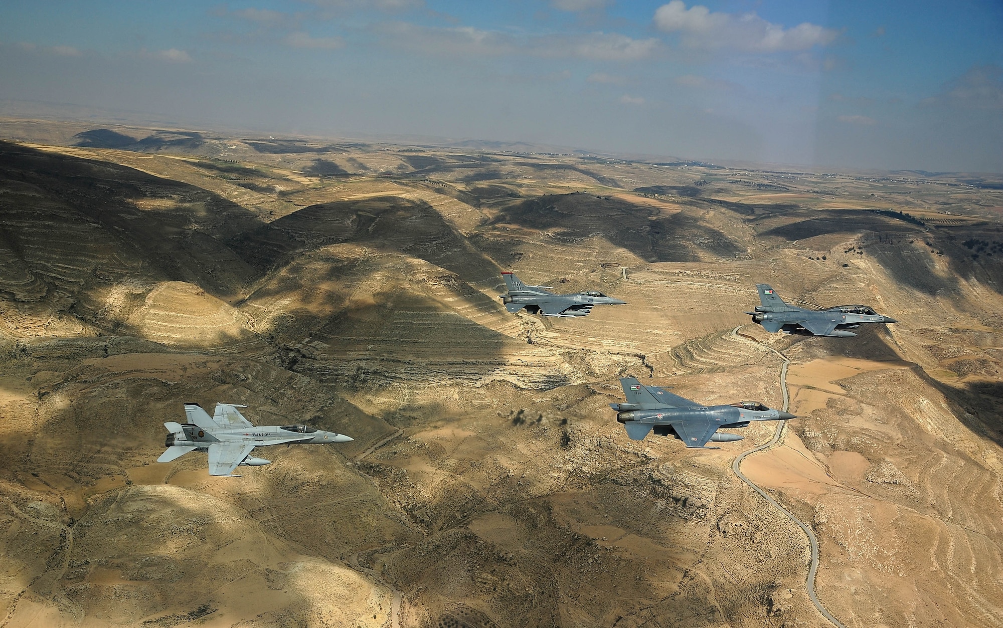 F-16 Fighting Falcons from the U.S. and Royal Jordanian air forces, as well as an F-18 Hornet from the U.S. Marine Corps, fly over Jordan May 13, 2014, during Exercise Eager Tiger. Hosted annually in Jordan, the exercise allows fighter pilots and maintainers from around the world to exchange knowledge while increasing interoperability and showing their dedication to regional stability. (U.S. Air Force photo by Staff Sgt. Roidan Carlson/Released)
