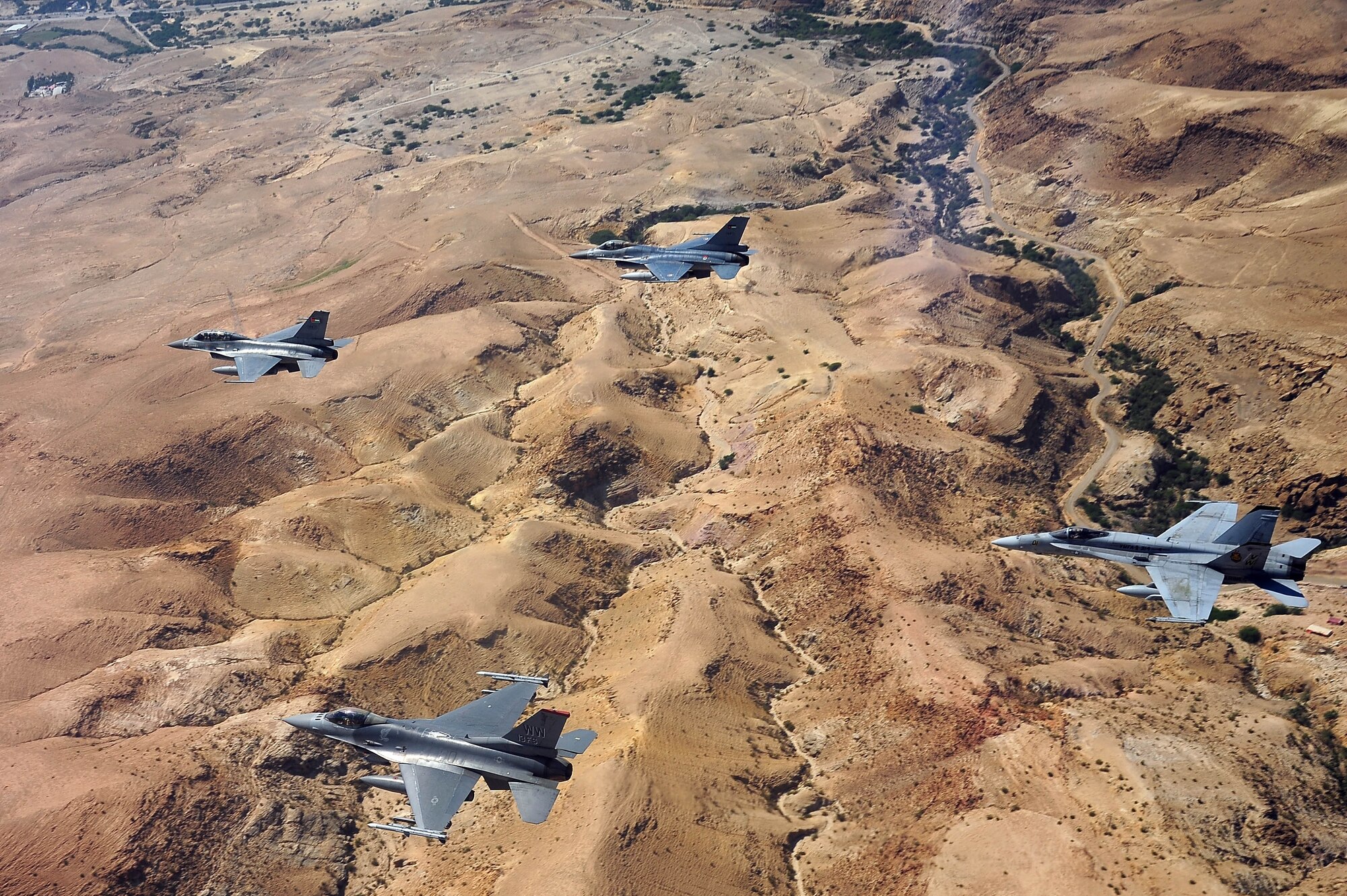 F-16 Fighting Falcons from the U.S. and Royal Jordanian air forces, as well as an F-18 Hornet from the U.S. Marine Corps, fly over Jordan May 13, 2014, during Exercise Eager Tiger. Hosted annually in Jordan, the exercise allows fighter pilots and maintainers from around the world to exchange knowledge while increasing interoperability and showing their dedication to regional stability. (U.S. Air Force photo by Staff Sgt. Roidan Carlson/Released)