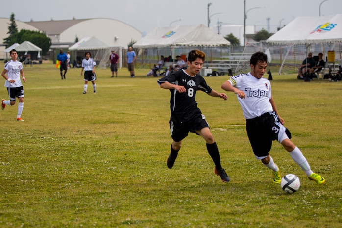 A player from U.S. Army Garrison Camp Zama, Japan, tries to slip past a player from Commander Fleet Activities Sasebo, Japan, during the Department of Defense Education Activities Far-East Division Two All-Boy Soccer Tournament aboard Marine Corps Air Station Iwakuni, Japan, May 19, 2014. The tournament is taking place May 19-22, 2014 aboard station.