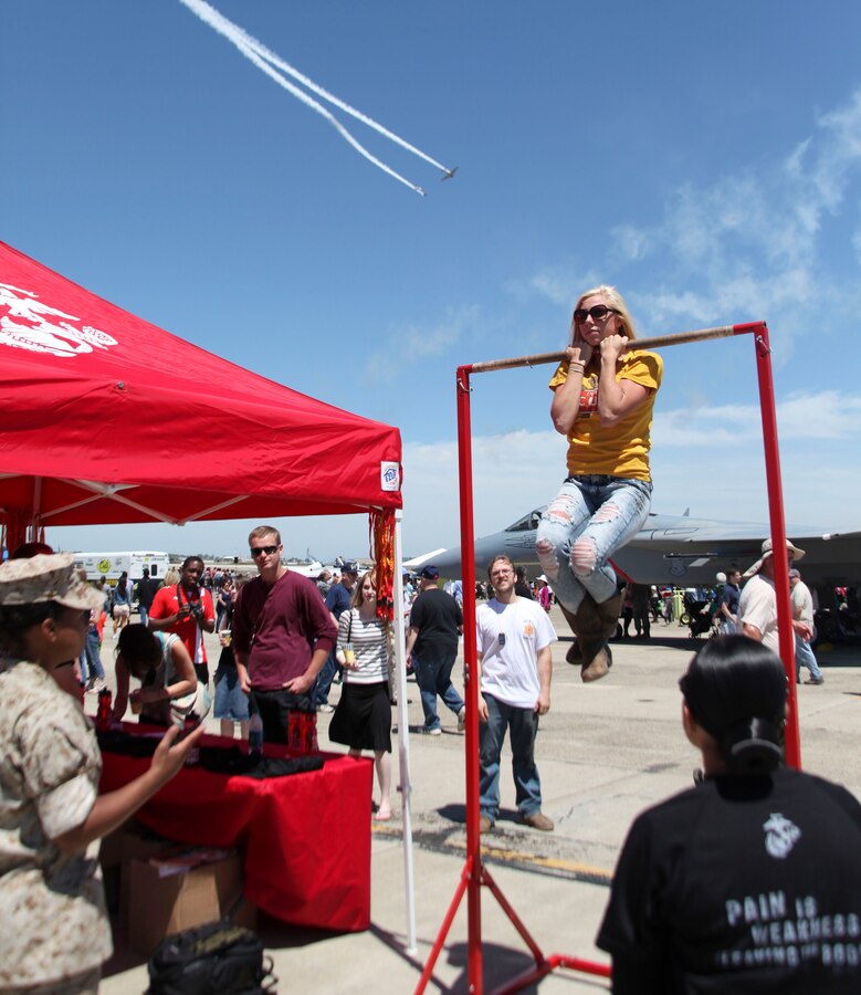 NORTH KINGSTON, R.I.—Laura Lavelle, a 22 year old from Uxbridge Mass., holds herself up on the pull-up bar for a total of 55 seconds while taking on the United States Marine Corps flexed arm hang challenge during the Rhode Island National Guard Open House and Air Show May 17. The airshow offers the finest aerial and static displays along with activities for people of all ages. (U.S. Marine Corps photo by Lance Cpl. Brandon Thomas)
