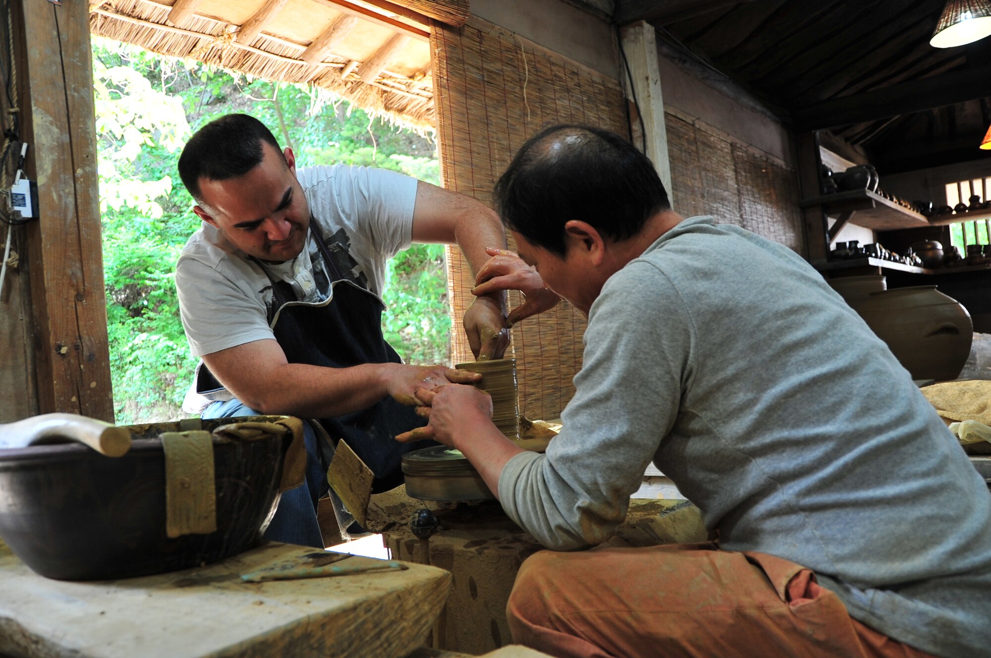 Tech. Sgt. Paul Cassidy, 7th Air Force A3/5, tries his hand at Korean pottery with the help of Lee Yong Hyun during a trip to the Korean Folk Village as part of the 7th Air Force Head Start Program May 16, 2014. The Head Start Program, funded by the government of Gyeonggi-do and taught by Pyeongtaek University, is a three-day program designed to introduce U.S. servicemembers and their families to Korean culture. The program has been open to members of 8th Army for eight years, but only recently became available to members of 7th Air Force here at Osan. The goal of the program is to give the members of Osan Air Base and their families a better understanding of the culture.  (U.S. Air Force photo by Tech. Sgt. Thomas J. Doscher)