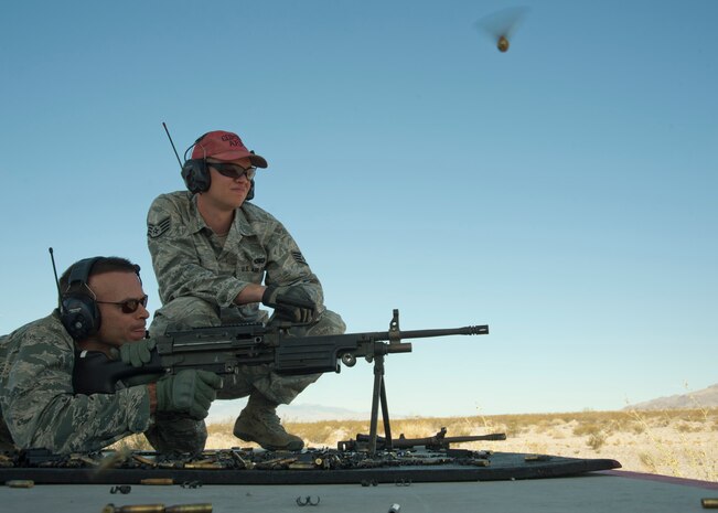 U.S. Air Force Staff Sgt. Michael Zema, 99th Security Forces Squadron combat arms instructor, observes as Col. Michael Kensick, 57th Operations Group commander, fires at distant targets with a M249 light machine gun during a base leadership familiarization event as part of National Police Week May 15, 2014, at Nellis Air Force Base Nev. The M249 light machine produces a maximum fire rate of 1,000 rounds per minute. (U.S. Air Force photo by Senior Airman Timothy Young)