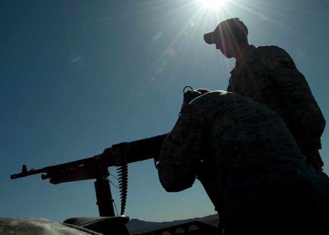 U.S. Air Force Staff Sgt. Jonathan Owens, 99th Security Forces Squadron combat arms instructor, guides Col. Michael Kensick, 57th Operations Group commander, while Kensick fires a M240B machine gun during a base leadership familiarization event as part of National Police Week May 15, 2014, at Nellis Air Force Base Nev. Leaders from around the base received hands-on experience with weapons that their members may use on occasion (U.S. Air Force photo by Senior Airman Timothy Young)