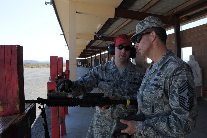 U.S. Air Force Senior Airman Zachary Barkhymer, 99th Security Forces Squadron combat arms instructor, answers questions about the M-4 carbine for Chief Master Sgt. Steven Cleveland, 99th Air Base Wing command chief, during a weapons familiarization event for base leadership in honor of National Police Week May 15, 2014, at Nellis Air Force Base, Nev.  Leaders from around the base were given the chance to get hands-on experience with weapons used during daily operations and missions while deployed. (U.S. Air Force photo by Tech. Sgt. Taylor Worley) 