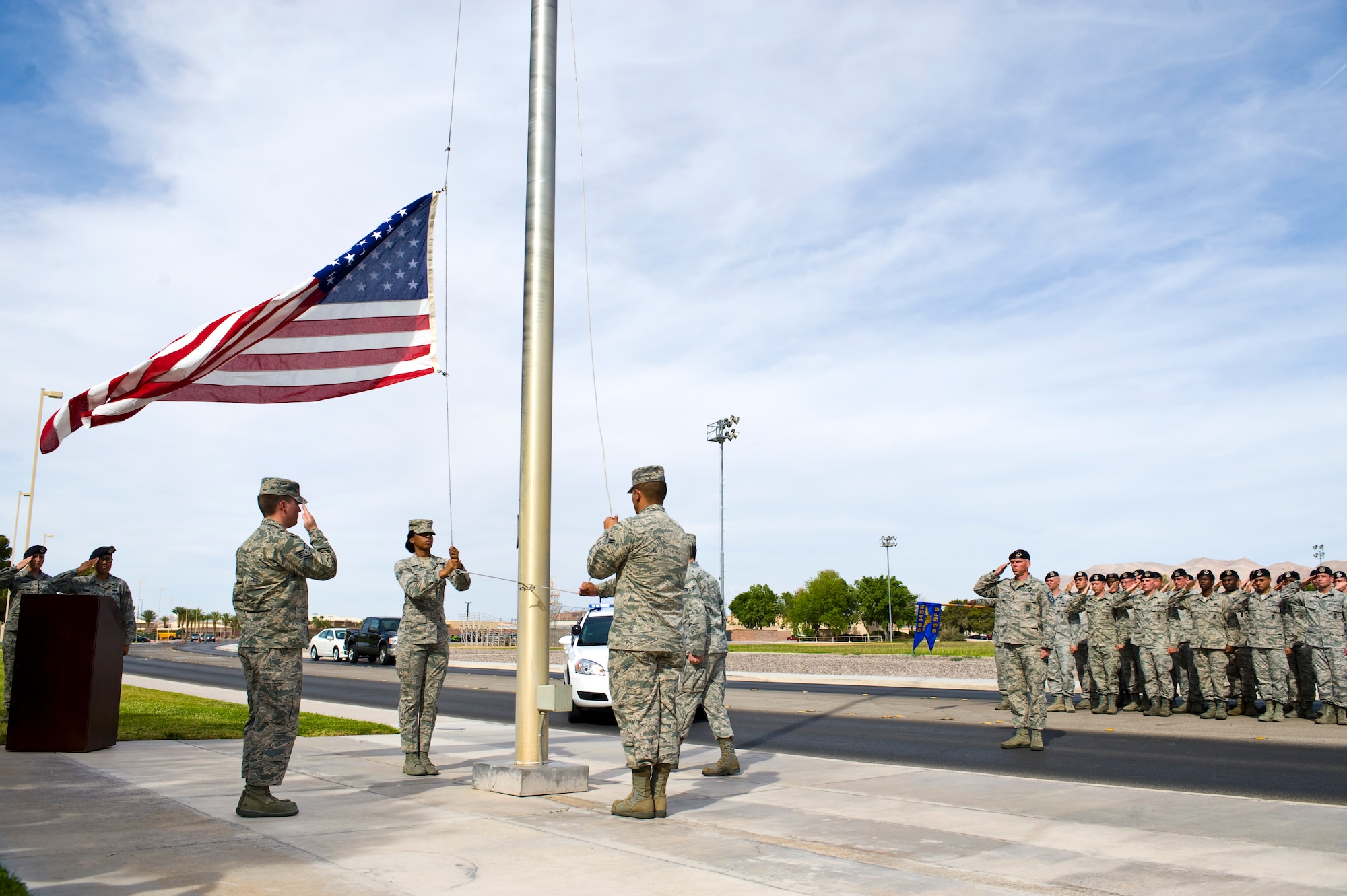 The Nellis Air Force Base Honor Guard, lower the U.S. flag as the 99th Security Forces Squadron renders salute at Freedom Park during a final guard mount and formal retreat ceremony as part of National Police Week May 16, 2014, at Nellis Air Force Base, Nev. National Police Week is celebrated annually during which all police forces are honored for their sacrifices. (U.S. Air Force photo by Senior Airman Christopher Tam)