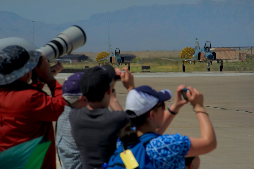 Visitors watch two F-4 Phantoms taxi the runway and prepare for takeoff during the Open House event at Holloman Air Force Base, N.M., May 10. Team Holloman hosted an Open House showcasing over 50 aircraft and the day-to-day duties of Holloman Airmen. With live flying demonstrations and static displays, thousands of guests attended the event to get a close-up look at the base’s assets and capabilities. Guests were able to view various aircraft, visit numerous vendors, and witness ground demonstrations from squadrons around the base. (U.S. Air Force photo by Airman 1st Class Aaron Montoya / Released)
