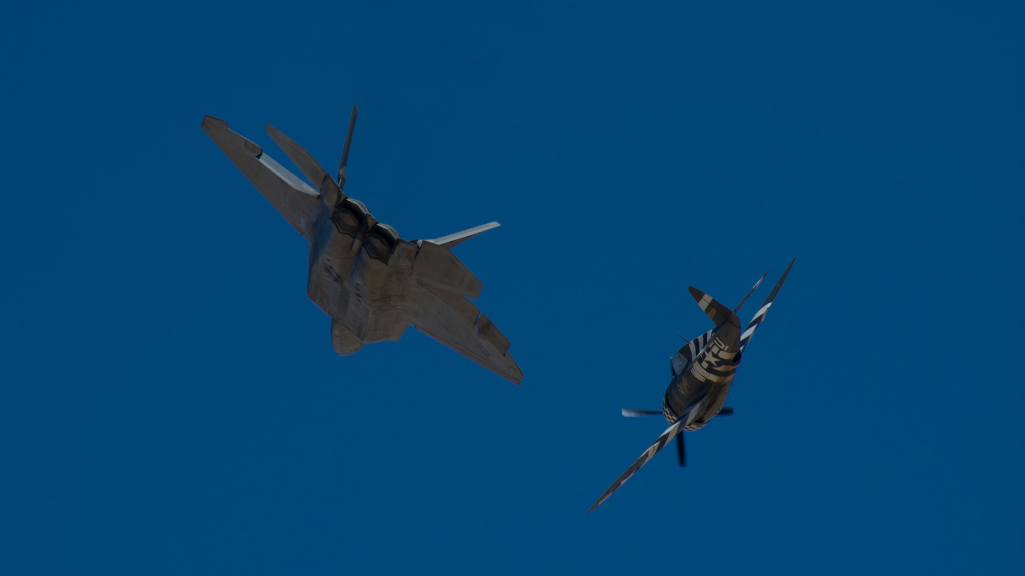 A P-47 Thunderbolt and an F-22 Raptor soar through the skies of the Tularosa Basin during the Open House event at Holloman Air Force Base, N.M., May 10. Team Holloman hosted an Open House showcasing over 50 aircraft and the day-to-day duties of Holloman Airmen. With live flying demonstrations and static displays, thousands of guests attended the event to get a close-up look at the base’s assets and capabilities. Guests were able to view various aircraft, visit numerous vendors, and witness ground demonstrations from squadrons around the base. (U.S. Air Force photo by Airman 1st Class Aaron Montoya / Released)