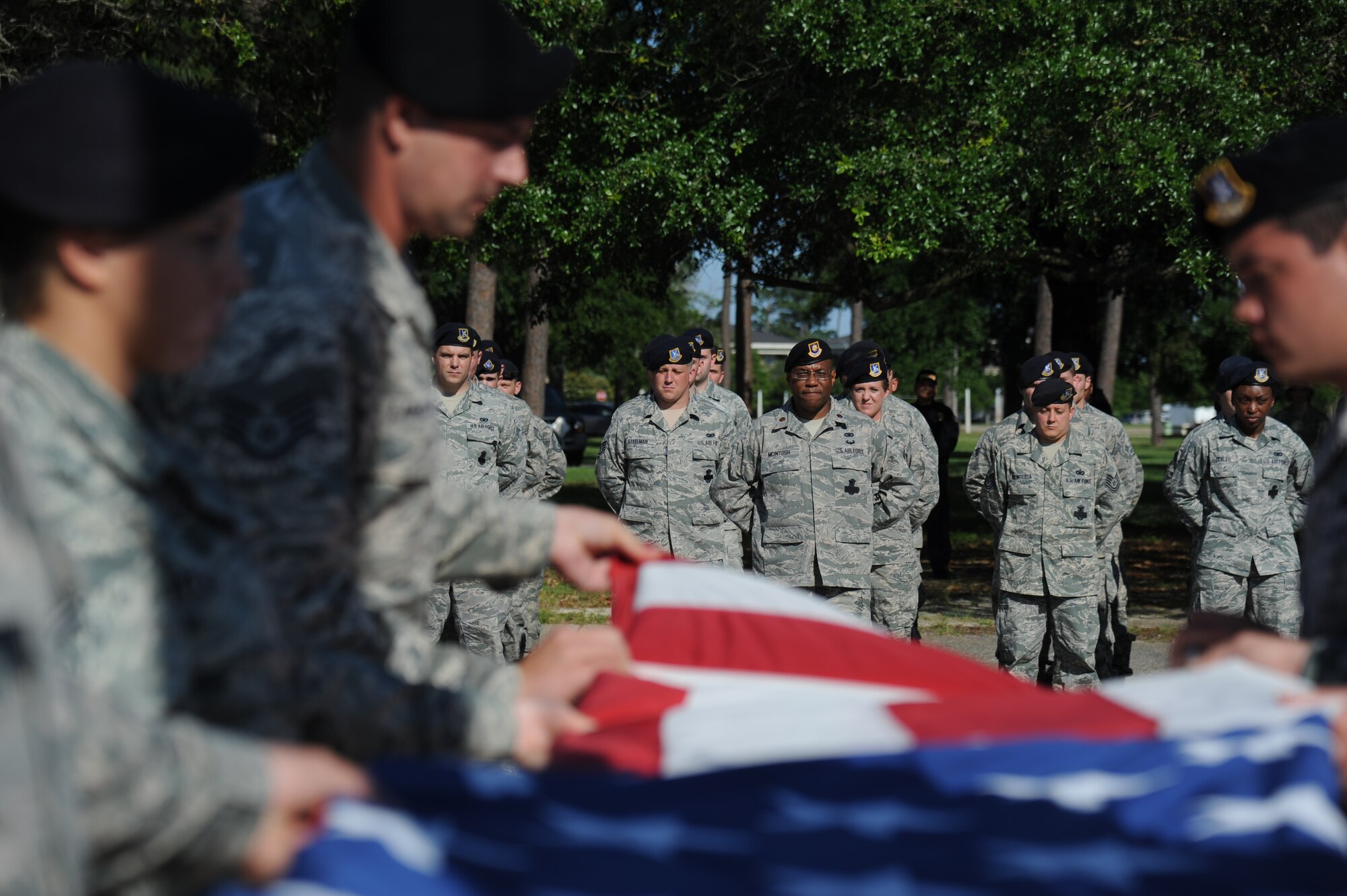 Maj. T.C. McIntosh, 81st Security Forces Individual Mobility Augmentee, and members of the 81st SFS stand at parade rest while a flag folding ceremony is conducted  during a retreat ceremony hosted by the 81st SFS May 15, 2014, at Keesler Air Force Base, Miss.  The retreat ceremony was held in memory of all law enforcement officers in the State of Mississippi, Air Force Officers of Special Investigations and 81st SFS members who have lost their lives in the line of duty over the past year.  (U.S. Air Force photo by Kemberly Groue)