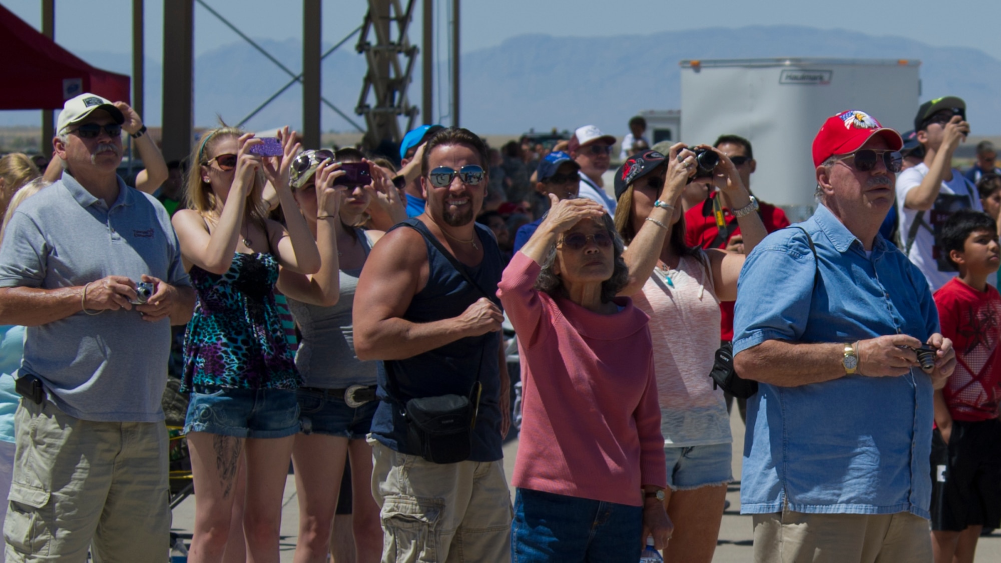 Visitors watch as aircraft fly over the Tularosa Basin during the Open House event at Holloman Air Force Base, N.M., May 10. Team Holloman hosted an Open House showcasing over 50 aircraft and the day-to-day duties of Holloman Airmen. With live flying demonstrations and static displays, thousands of guests attended the event to get a close-up look at the base’s assets and capabilities. Guests were able to view various aircraft, visit numerous vendors, and witness ground demonstrations from squadrons around the base. (U.S. Air Force photo by Airman 1st Class Aaron Montoya / Released)