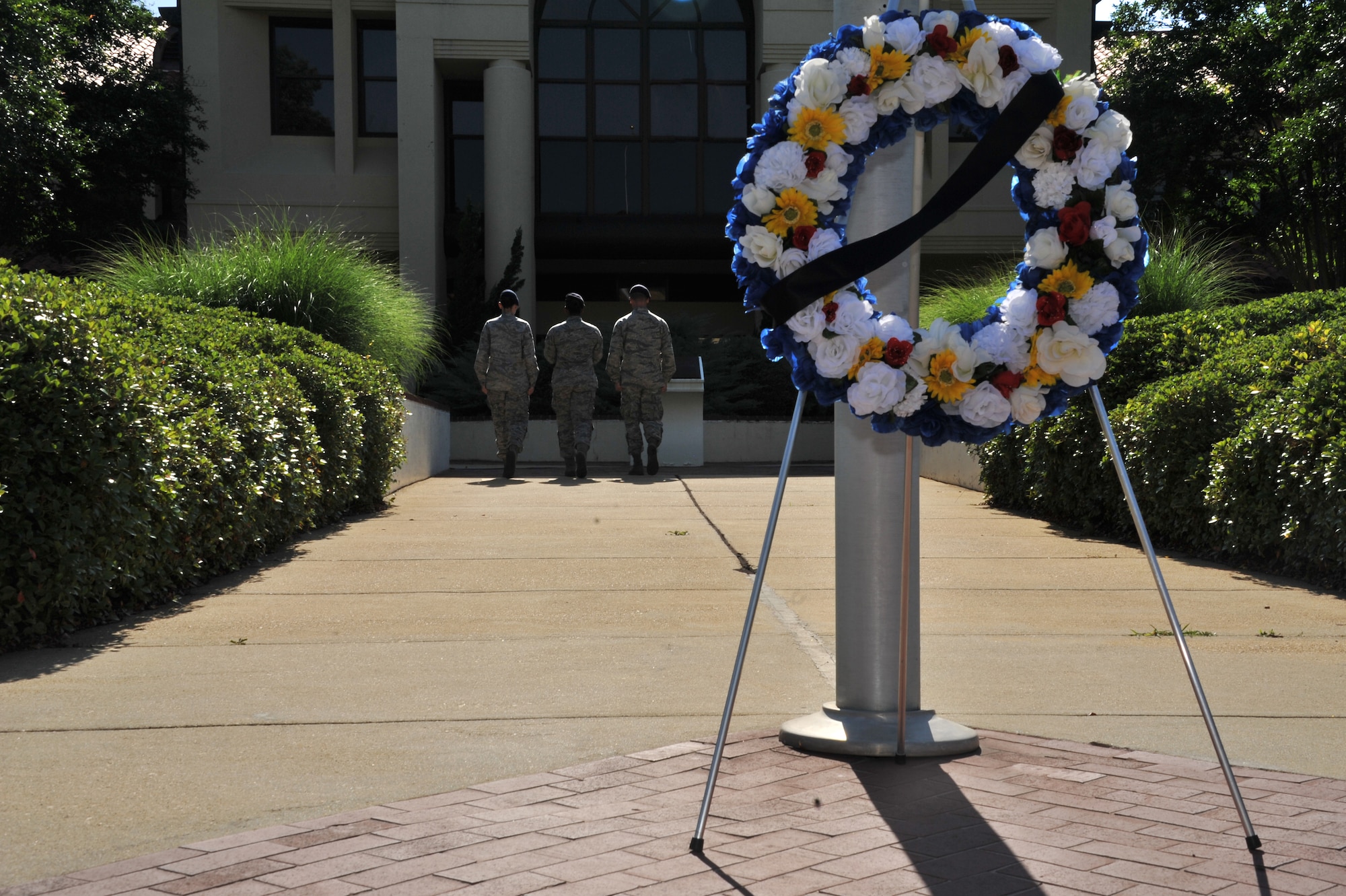 The 42nd Security Forces Squadron flag detail marches the flag to their building as a commemoration wreath stands for all to see during a National Police Week retreat ceremony here, May, 16, 2014. The 42nd SFS hosted the ceremony to pay tribute to civilian and military law enforcement, who made the ultimate sacrifice in the line of duty. (U.S. Air Force photo by Staff Sgt. Natasha Stannard)