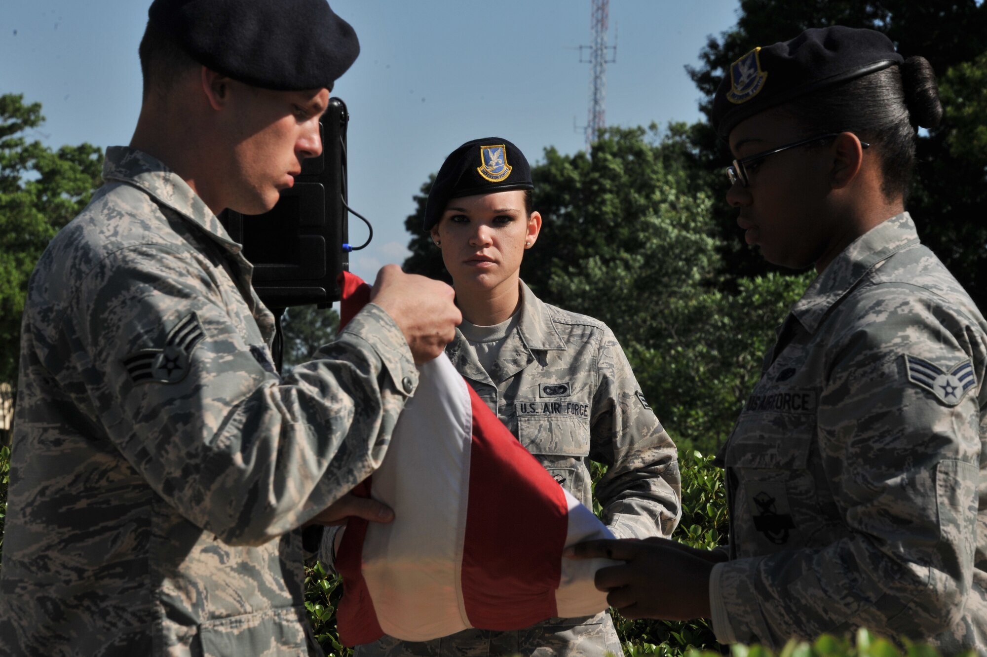 Airman 1st Class Brittany Moore, 42nd Security Forces Squadron, holds the flag steady as her comrades fold it during a National Police Week retreat ceremony here, May, 16, 2014. The retreat ended the police week activities, which all took place to recognize the selfless sacrifice of defenders and civilian law enforcement. (U.S. Air Force photo by Staff Sgt. Natasha Stannard.)