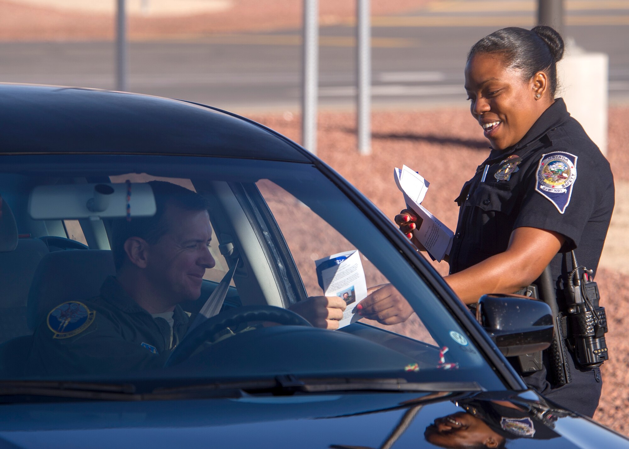 Nevada highway patrol officer Jineal Jack hands a Police Week flyer to an Airman passing through the gates of Creech Air Force Base, Nev., on May 12, 2014. Police Week is a nation-wide event proclaimed by the president of the United States during the week of May 15 each year to recognize all law enforcement officers who have paid the ultimate sacrifice. (U.S. Air Force photo by; Airman 1st Class C.C./Released)