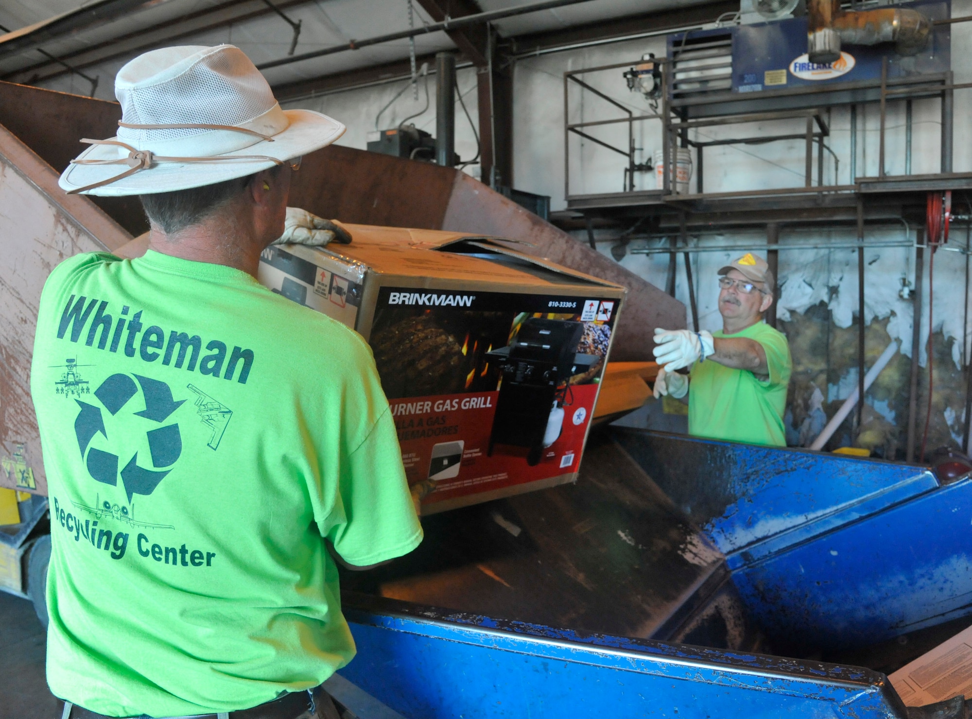 Eric Goewey, 509th Force Support Squadron material examiner and identifier, left, and Mark Davis, 509th FSS recycling center supervisor, unload cardboard into the baler at Whiteman Air Force Base, Mo., May 7, 2014. The baler is used to compress and convert cardboard into bales to ship to companies. (U.S. Air Force photo by Airman 1st Keenan Berry/Released).