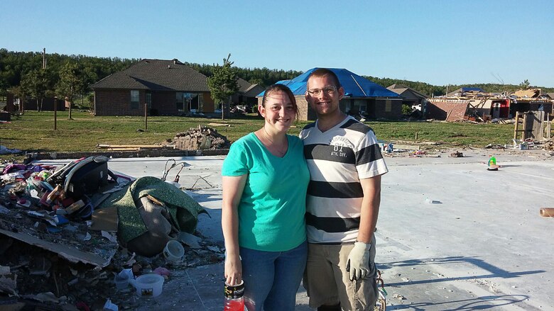 Tiffany and Senior Airman Drew Baker in front of what’s left of their home in Vilonia, Arkansas.  An EF4 tornado ripped through central Arkansas April 27, killing 16 people.  The Baker’s dog, Batman, was in a metal kennel in the house when the storm hit, and was found unharmed more than a mile away. More than 15 bags of donated items were collected from members of Baker’s unit, 22nd Air Force, Detachment 1, Air Force Reserve Command. (Photo provided by Senior Airman Drew Baker.)