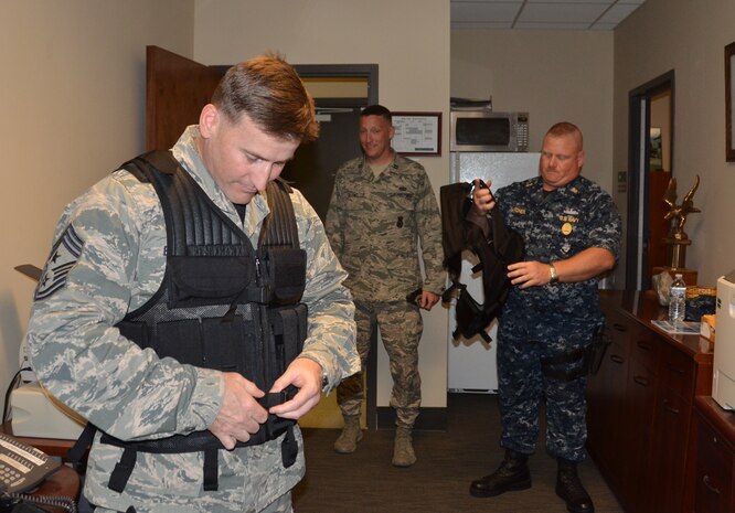 Capt. Jonathan Blount, 628th Security Forces Squadron (center) watches as Chief Master Sgt. Mark Bronson, 628th Air Base Squadron command chief and Master Chief Petty Officer Joseph Gardner, Naval Support Activity command master chief, don the gear they will be using during their “ride-a-long” with Security Forces personnel May 14, 2014, at Joint Base Charleston – Weapons Station, S.C. Bronson and Gardner, along with Joint Base Charleston Commander Col. Jeffrey DeVore, were visiting the 628th SFS as part of a program designed to give base leaders a taste of what Airmen and Sailors do at their job centers every day. (U.S. Air Force photo/Eric Sesit)