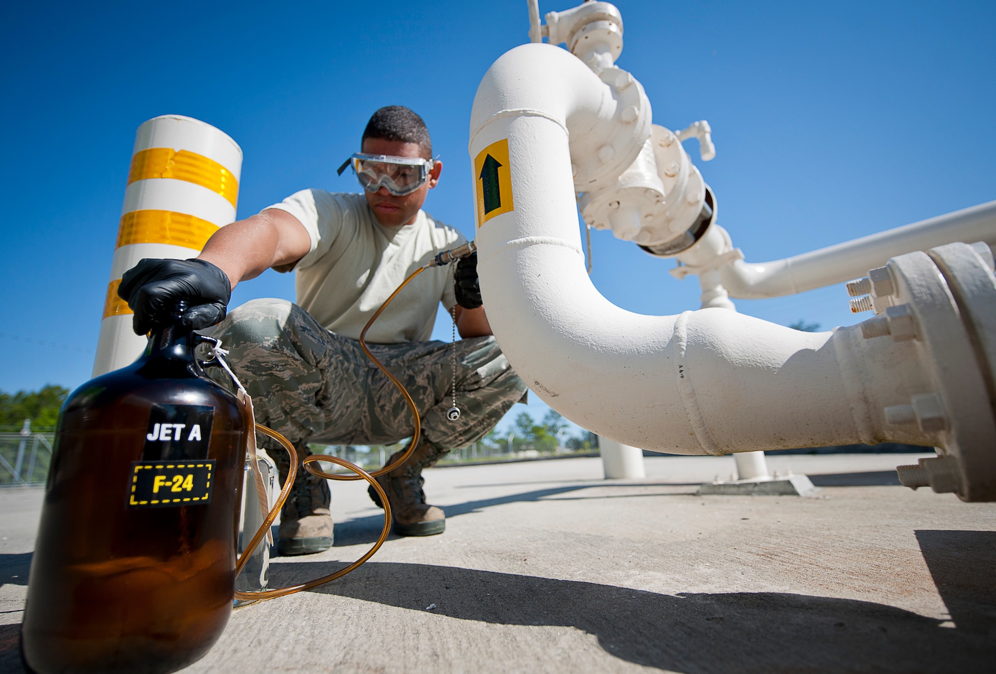 Senior Airman Troy Hall, the 96th Fuels Flight, takes a sample of Jet-A fuel from a pipe while the fuel is being offloaded from a truck May 6 at Eglin Air Force Base, Fla.  Fuel samples are taken to check if water and sediment amounts are detected.  (U.S. Air Force photo/Samuel King Jr.)