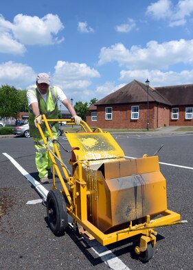Contractor Kyle McFetridge repaints lines in a parking lot May 19, 2014, on RAF Mildenhall, England. Every few years, roads and parking lots must be repainted to ensure driver safety, increase marking visibility and maintain the base’s appearance. (U.S. Air Force photo by Airman 1st Class Preston Webb/Released)