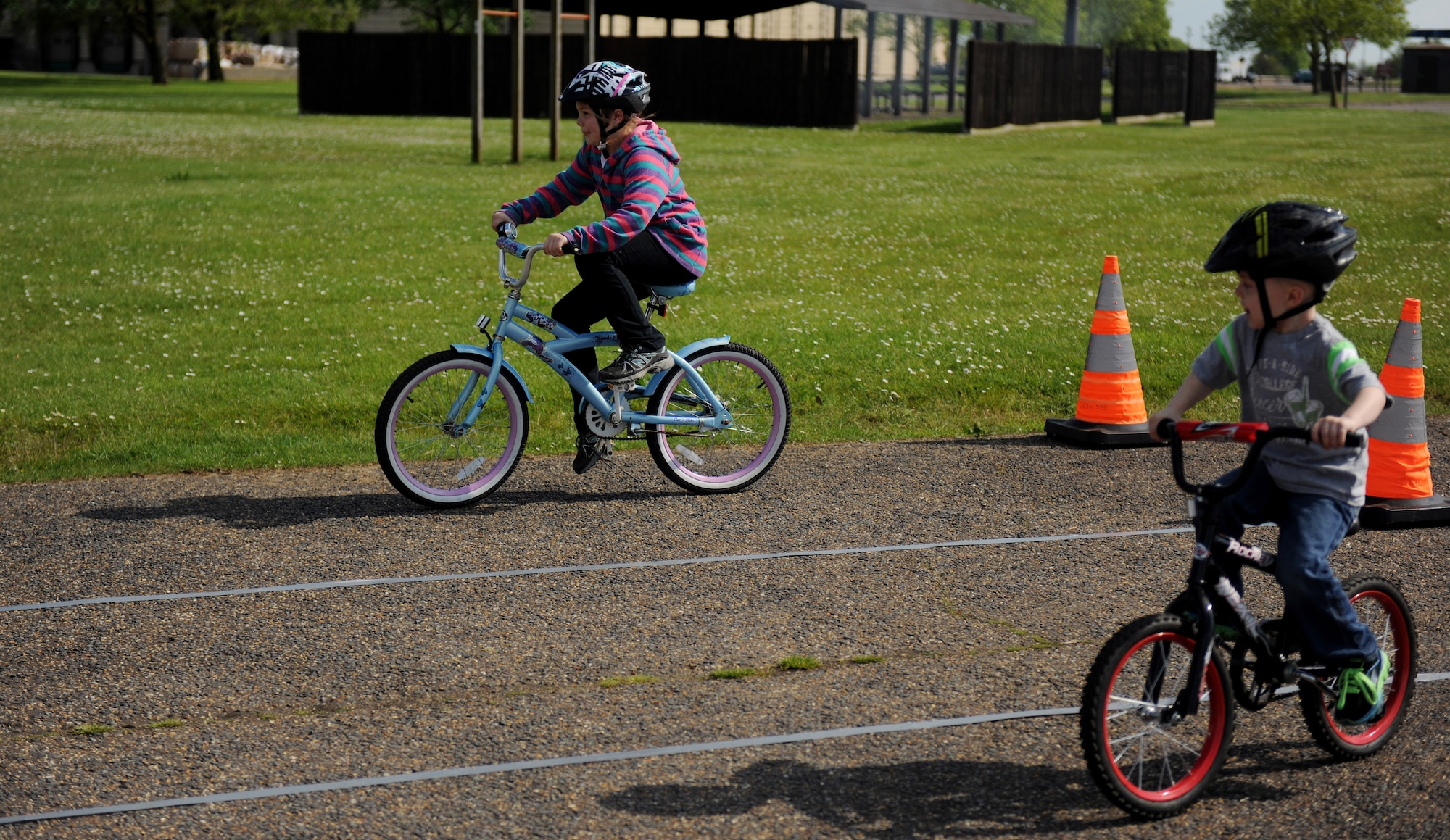Two military children race their bikes through an obstacle course at RAF Alconbury, May 14, 2014. The obstacle course was part of a bike safety rodeo, designed to teach children the importance of good riding habits. (U.S. Air Force photo by Staff Sgt. Jarad A. Denton/Released)