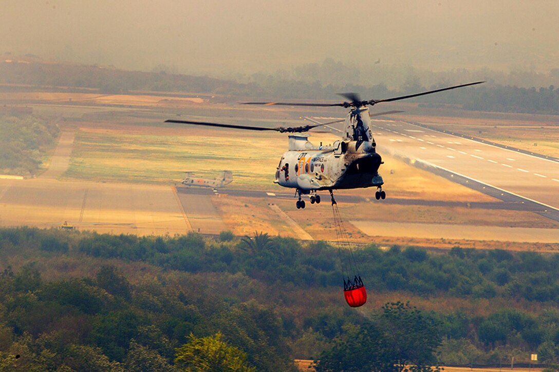 A U.S. Marine Corps CH-46 Sea Knight helicopter helps fight fires and contain the Cocos fire in San Marcos, Calif., May 16, 2014.