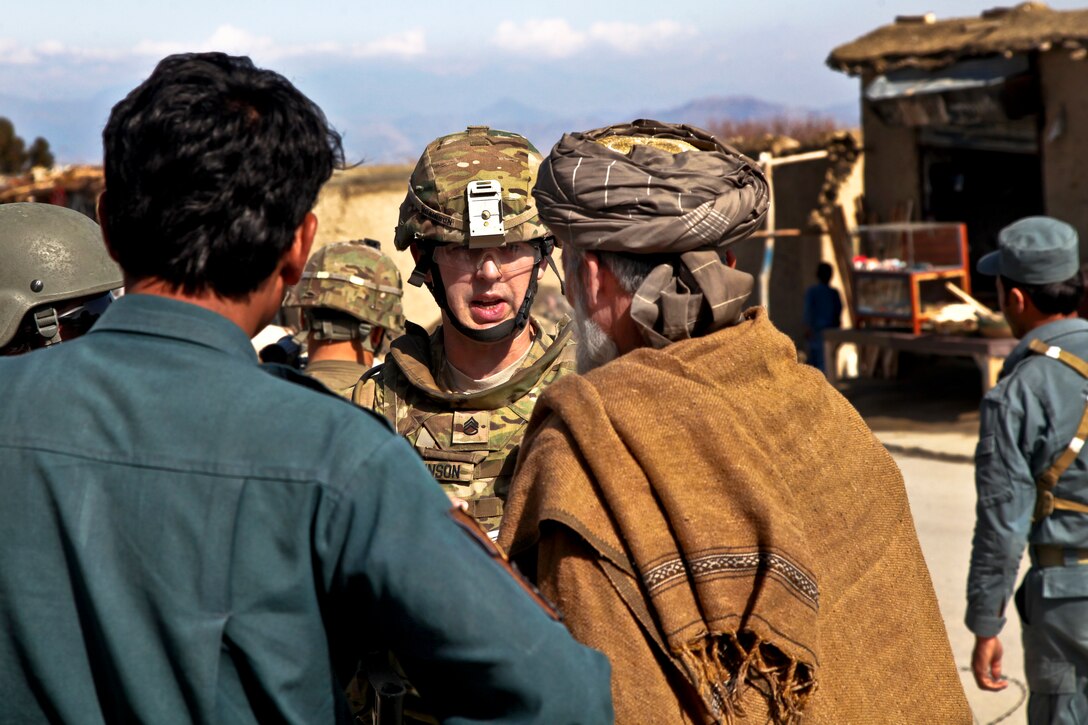U.S. Army Staff Sgt. Thomas Robinson, center, asks an Afghan police officer and resident about their welfare and related topics during security operations at the Chaparhar district center in Afghanistan's Nangarhar province, Feb. 23, 2013. Robinson is assigned to the 101st Airborne Division's 1st Brigade Combat Team and Provincial Reconstruction Team Nangarhar.  
