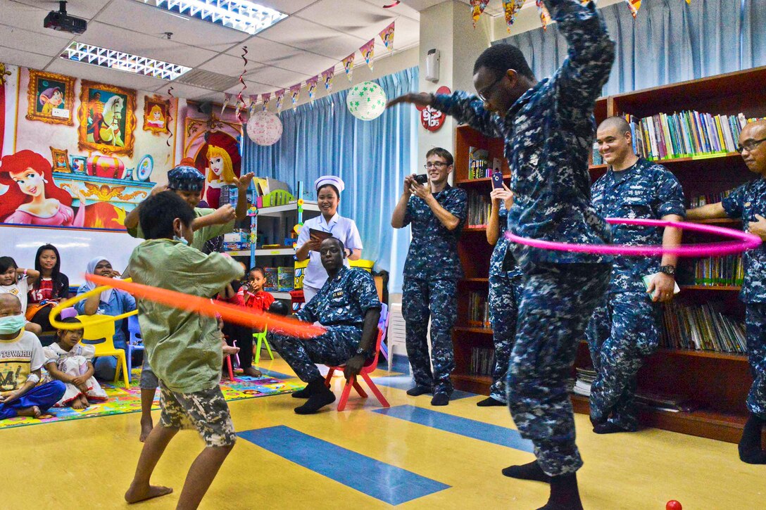 U.S. Navy Petty Officer 3rd Class Tarwon Koah challenges patients from the Likas Hospital's cancer unit to a hula-hoop contest in Kota Kinabalu, Malaysia, March 1, 2013. The U.S. sailors volunteered while in port to entertain children in the child cancer and blood transfusion wards, reading, playing games, music and dancing. Koah is assigned to the submarine tender USS Frank Cable. 
