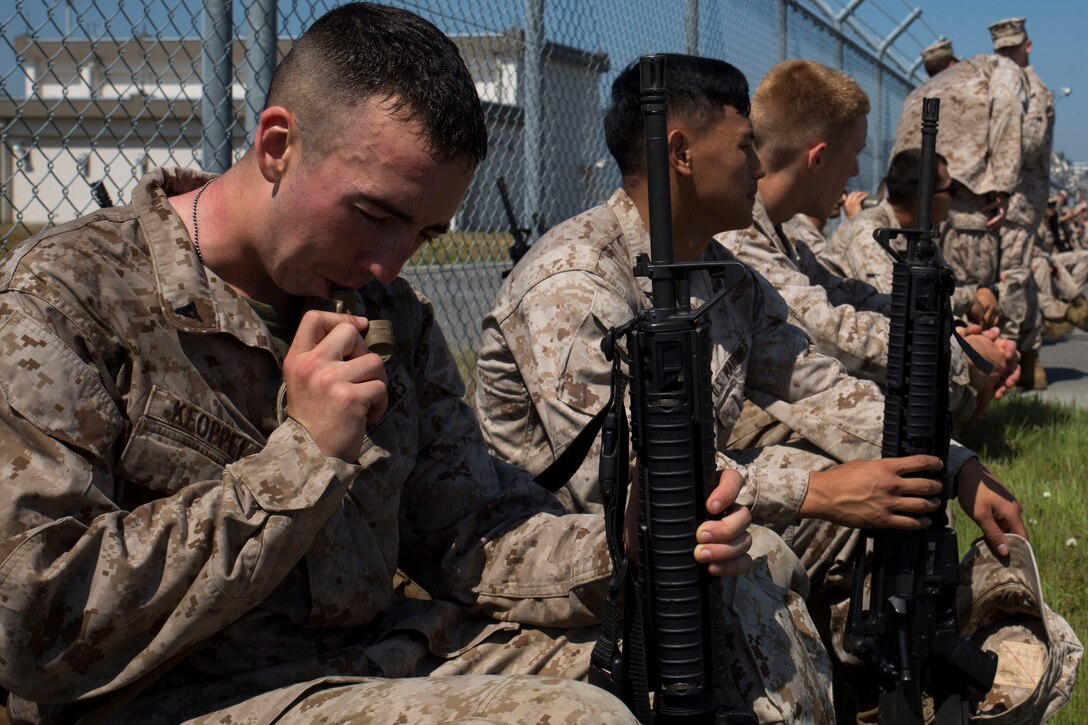 Marines with Marine Wing Support Squadron 171 take a moment to catch their breath and hydrate after reaching the halfway point of their six-mile conditioning hike aboard Marine Corps Air Station Iwakuni, Japan, May 16, 2014. The hike purpose is to build camaraderie and unit cohesion, as well as establish a combat mindset in the Marines.