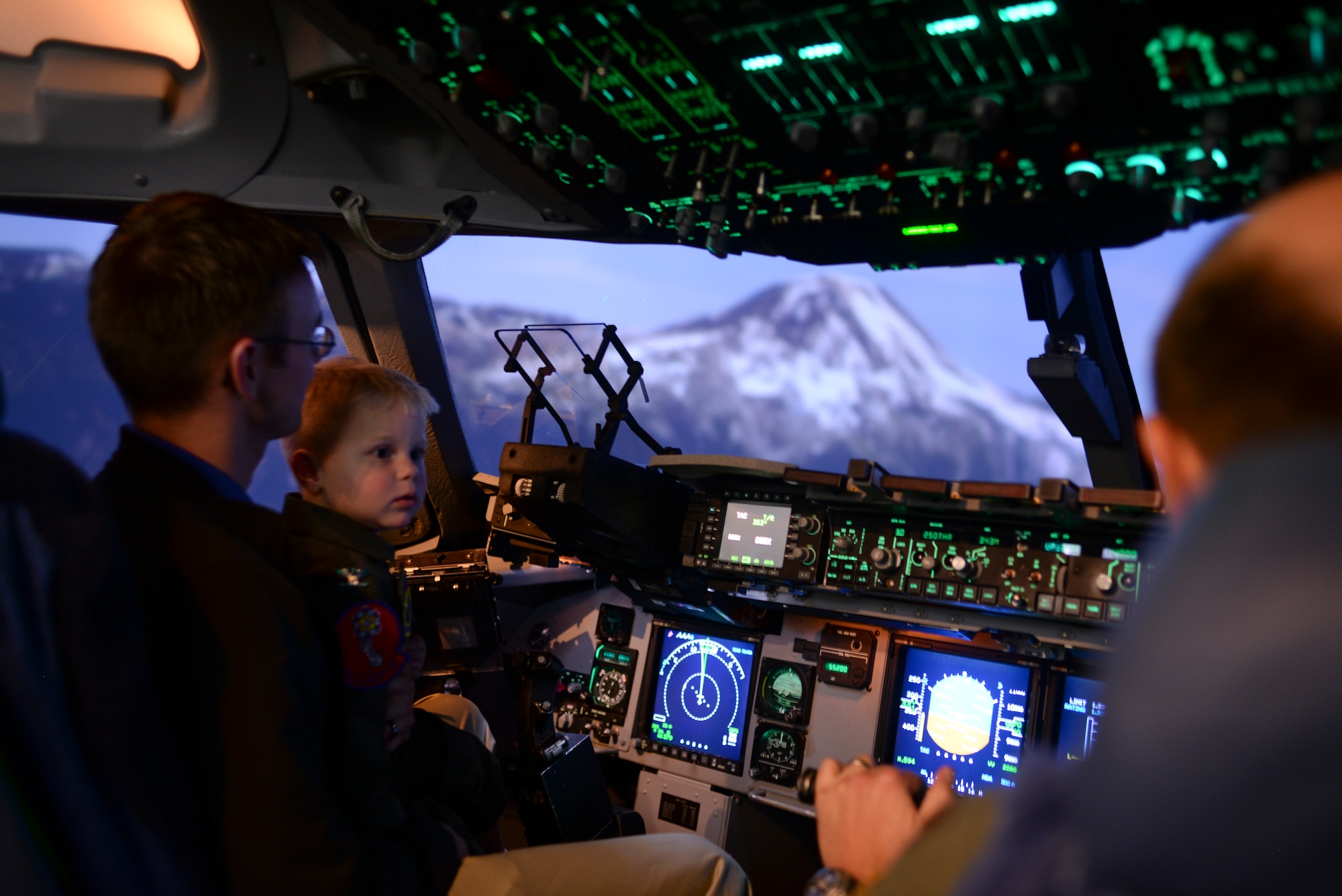Maj. Erick Brough flies two-year-old John Austin and his father, Jason, past Mount Rainier, Wash., in a C-17 Globemaster III flight simulator May 15, 2014. The Austin family visited Altus Air Force Base and explored airplanes, fire trucks and the base air traffic control tower. (U.S. Air Force photo/Staff Sgt. Nathanael Callon) 