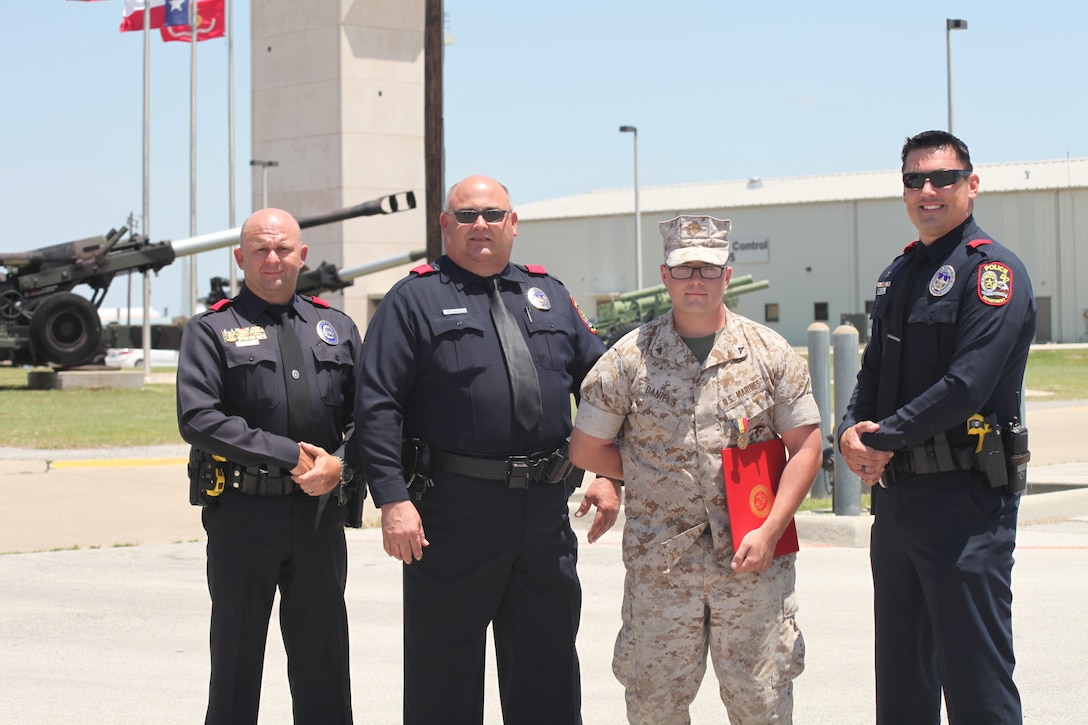 Lance Cpl. Bryan Daniels, motor transport operator with Headquarters Battery, 14th Marine Regiment, poses for a photo with members of the Grand Prairie Police Department, Wes Bement (left), Mark Calvert (center), and Nick Steppe (right) May 18, 2014. The officers were first responders on the scene when Daniels attempted to rescue a driver trapped in a burning tractor-trailer last August. Daniels was awarded the Navy and Marine Corps Medal for his actions.(Official Marine Corps Photo by Staff Sgt. Joel Chaverri)