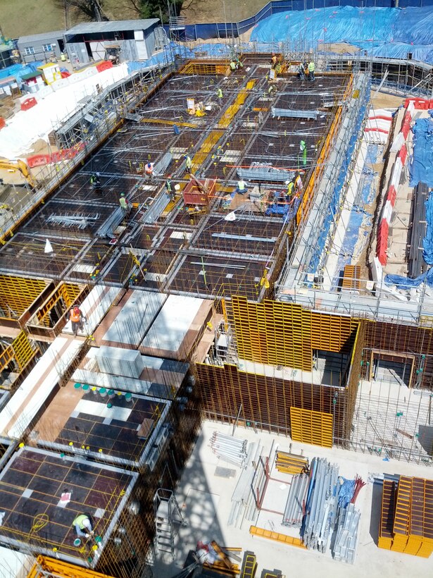 Construction on an 8-story barracks continues at Camp Carroll using the down slab form system and form uplifting robot, a new technology that provides a safer and more efficient way to mold concrete walls and floors.