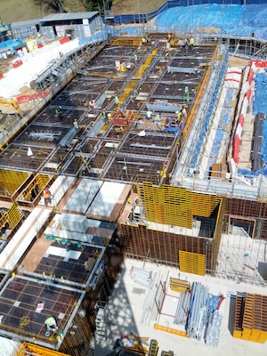 Construction on an 8-story barracks continues at Camp Carroll using the down slab form system and form uplifting robot, a new technology that provides a safer and more efficient way to mold concrete walls and floors.
