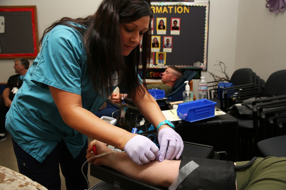 Tabitha Riess, Donor Specialist, inserts a needle into the arm of Pfc. Chase Gross, student, Marine Corps Communication-Electronics School, to begin drawing blood during a blood donation event hosted by Headquarters Battalion and Desert Blood Services at the base Catholic chapel April 22, 2014. Desert Blood Services comes to the Combat Center frequently and travels from unit to unit to give service members and Combat Center patrons an opportunity to donate.