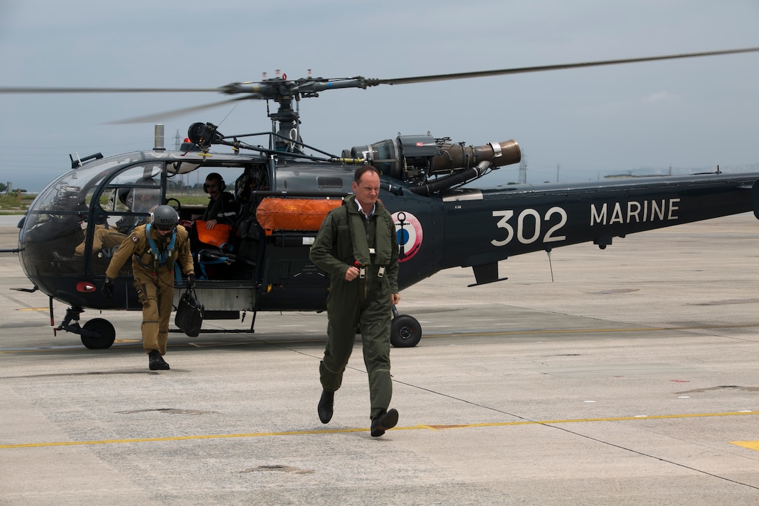 French Navy Capt. Francois Duhamez, center, exits from an Aerospatiale Alouette III helicopter May 19, 2014 at Marine Corps Air Station Futenma, Okinawa, Japan. Duhamez’s visit demonstrated the French Armed Forces’ ability to land aircraft at designated United Nations staging points under the status of forces agreement between the U.N. and government of Japan. Duhamez is a French defense attaché with the U.N. Command.